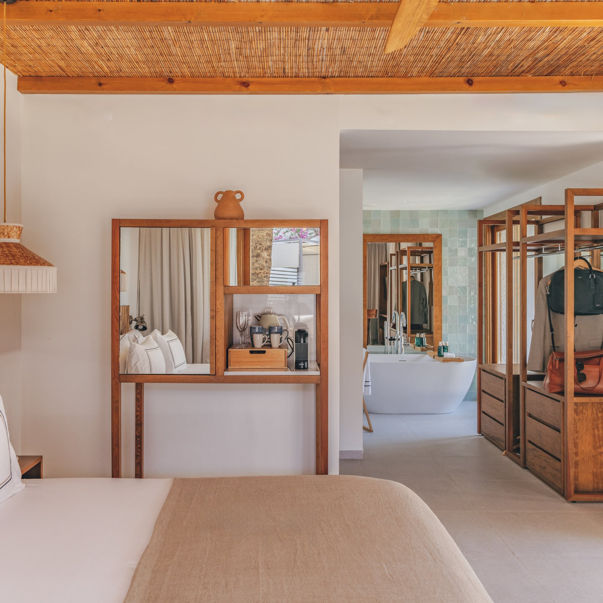 Modern hotel bedroom with open wood closet, bamboo ceiling, and bathroom.