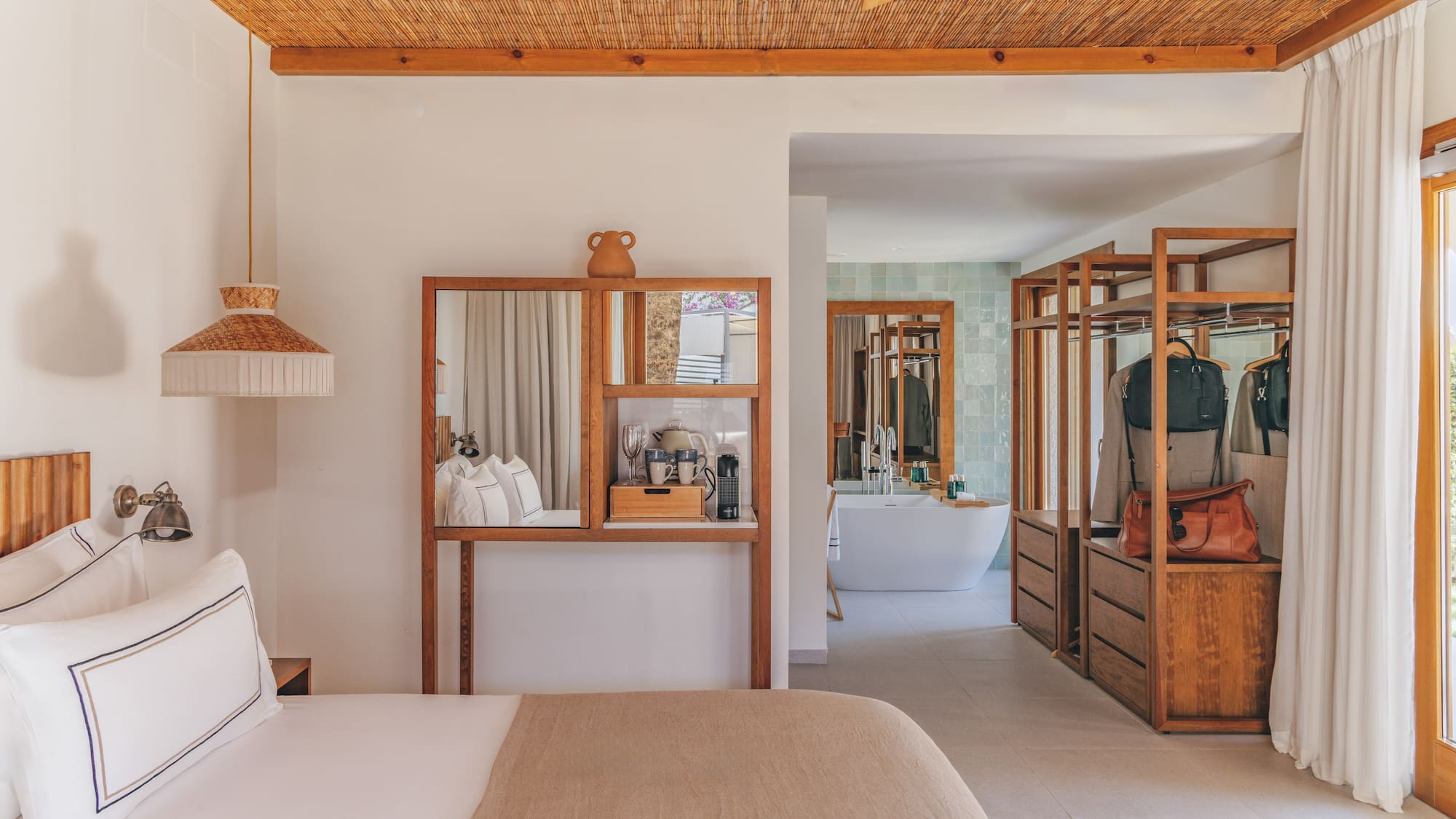 Modern hotel bedroom with open wood closet, bamboo ceiling, and bathroom.