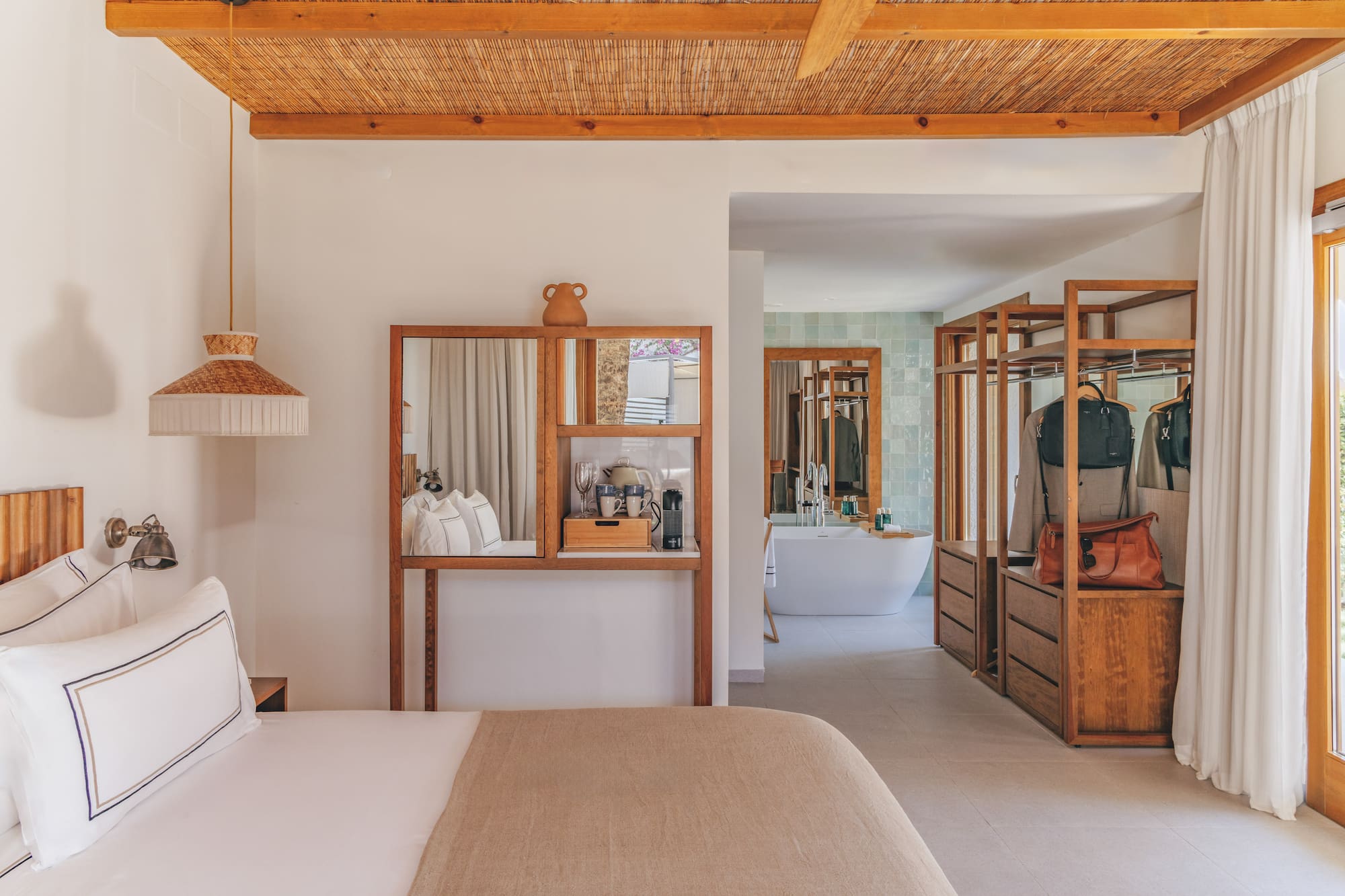 Modern hotel bedroom with open wood closet, bamboo ceiling, and bathroom.