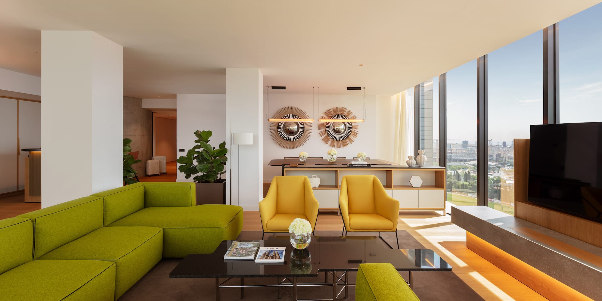 Bright modern living room with green sofa, yellow chairs, city view.