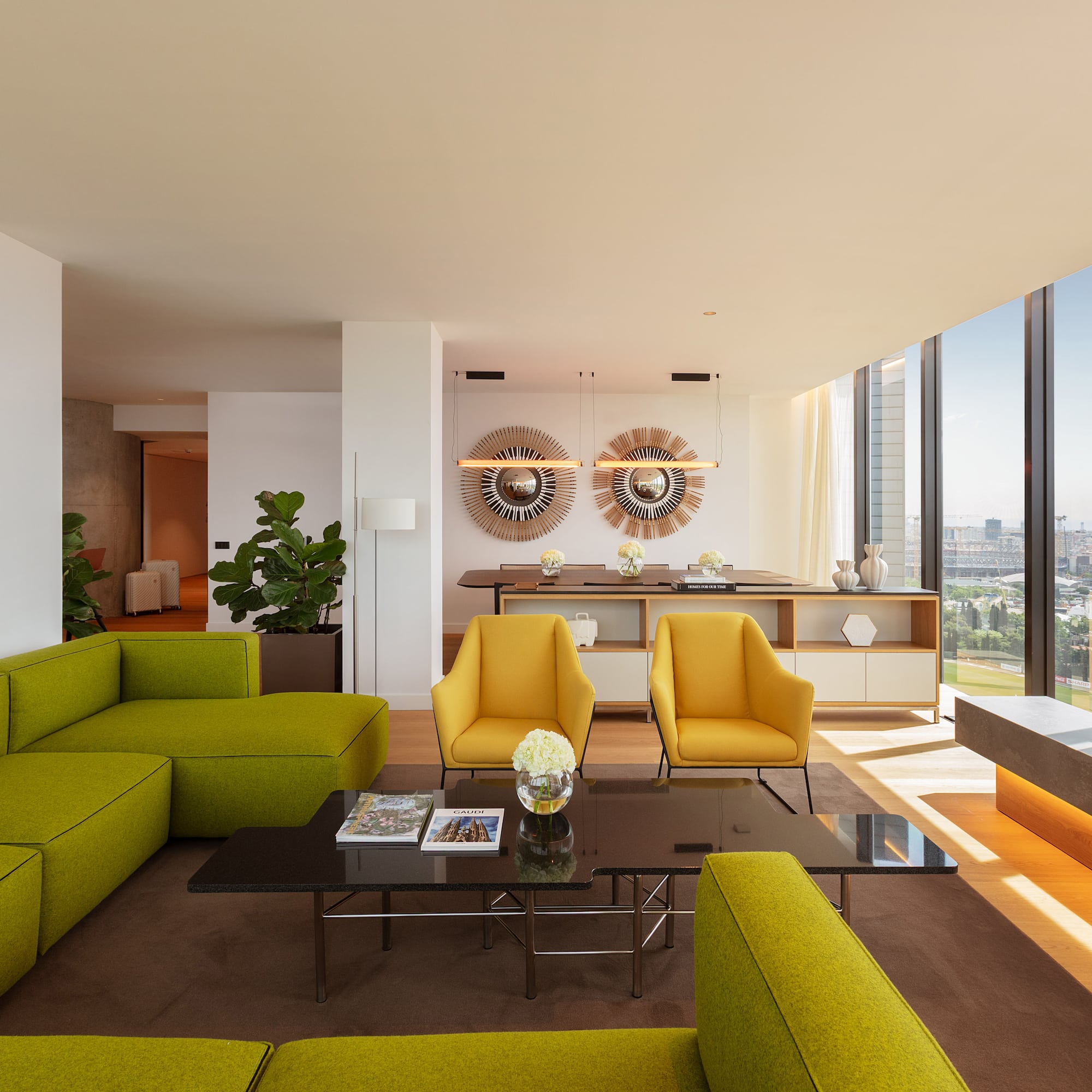 Modern living room with green sofa, yellow chairs, and city view.