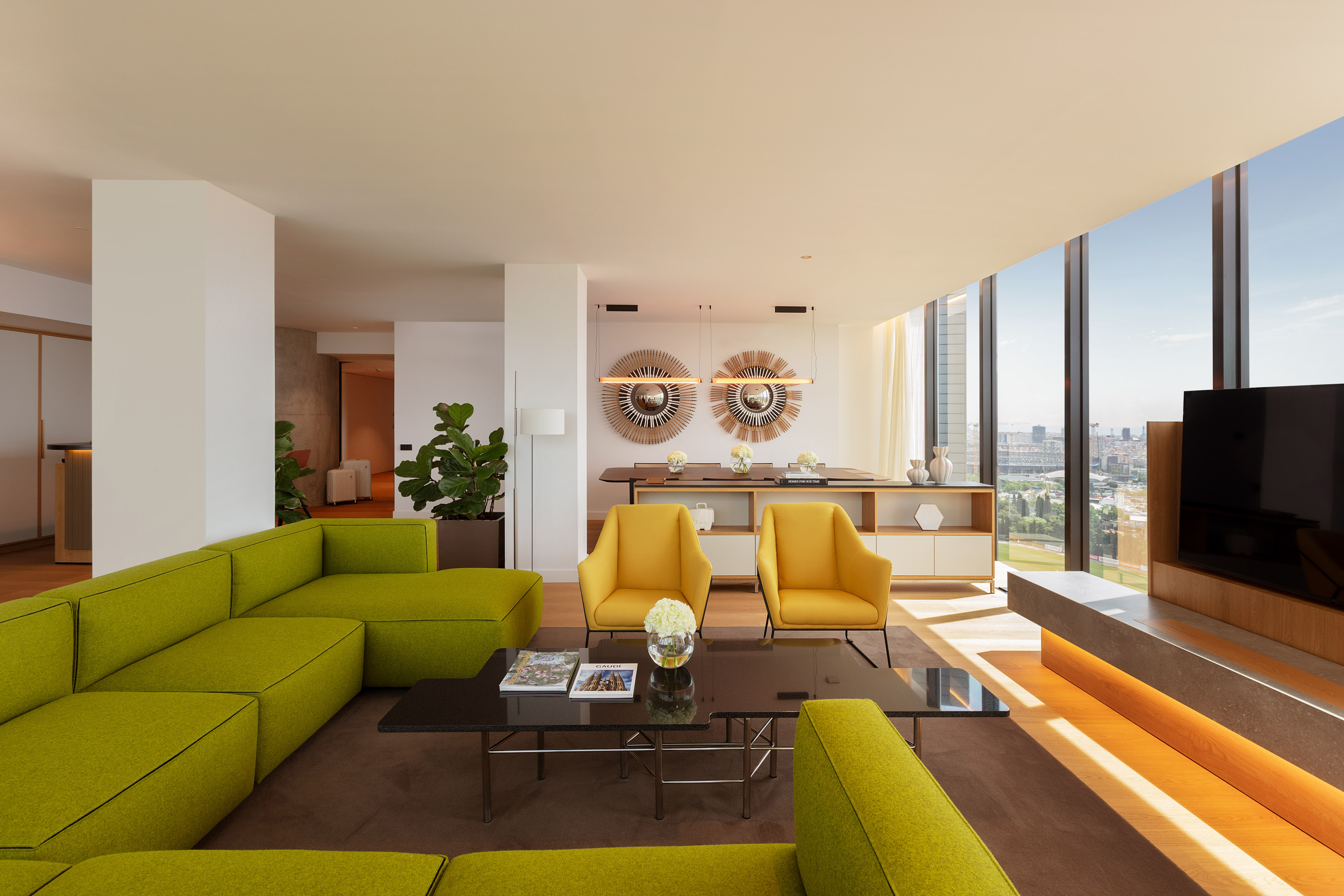 Modern living room with green sofa, yellow chairs, and city view.