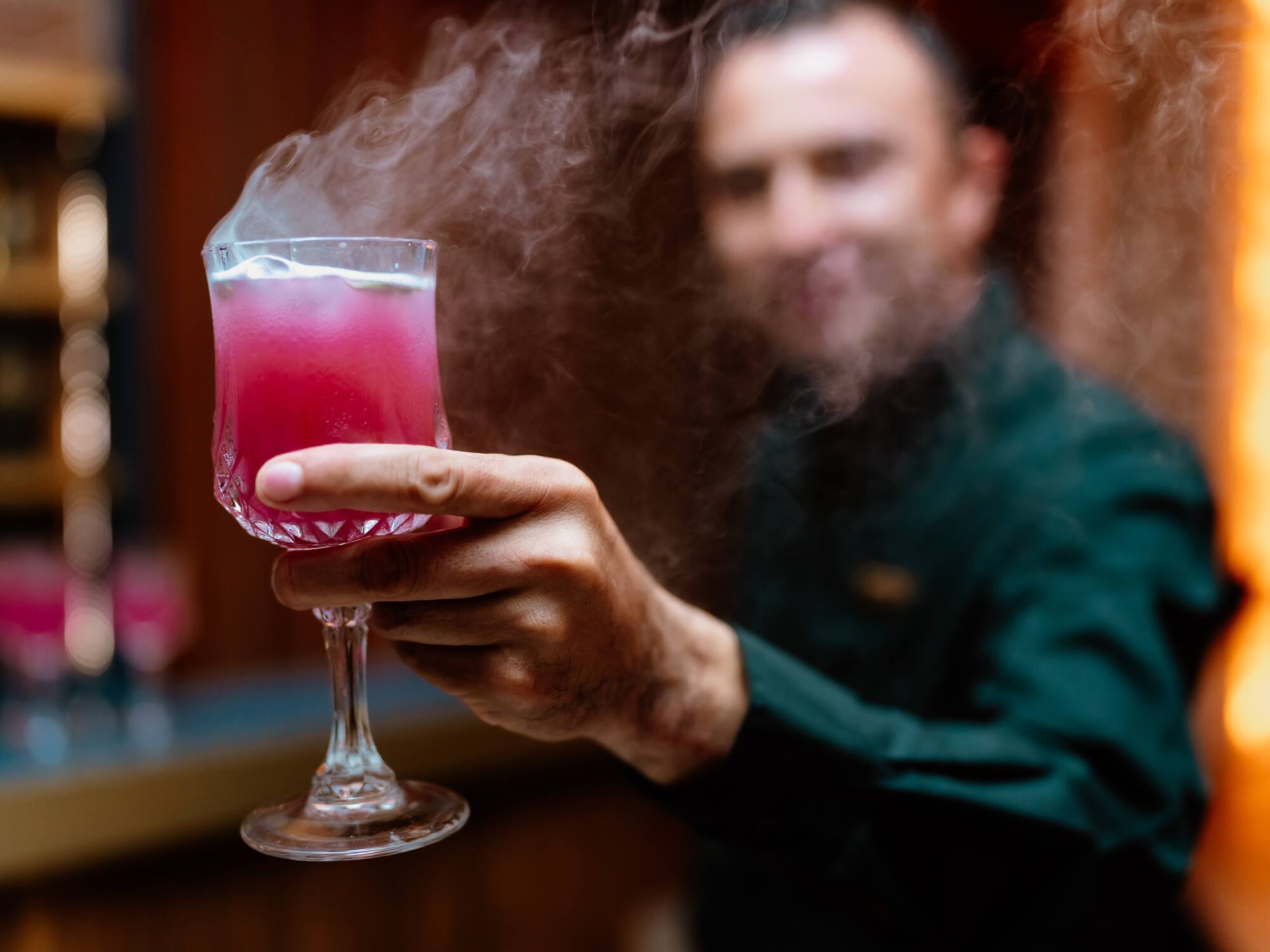 a man holding a glass with a pink drink
