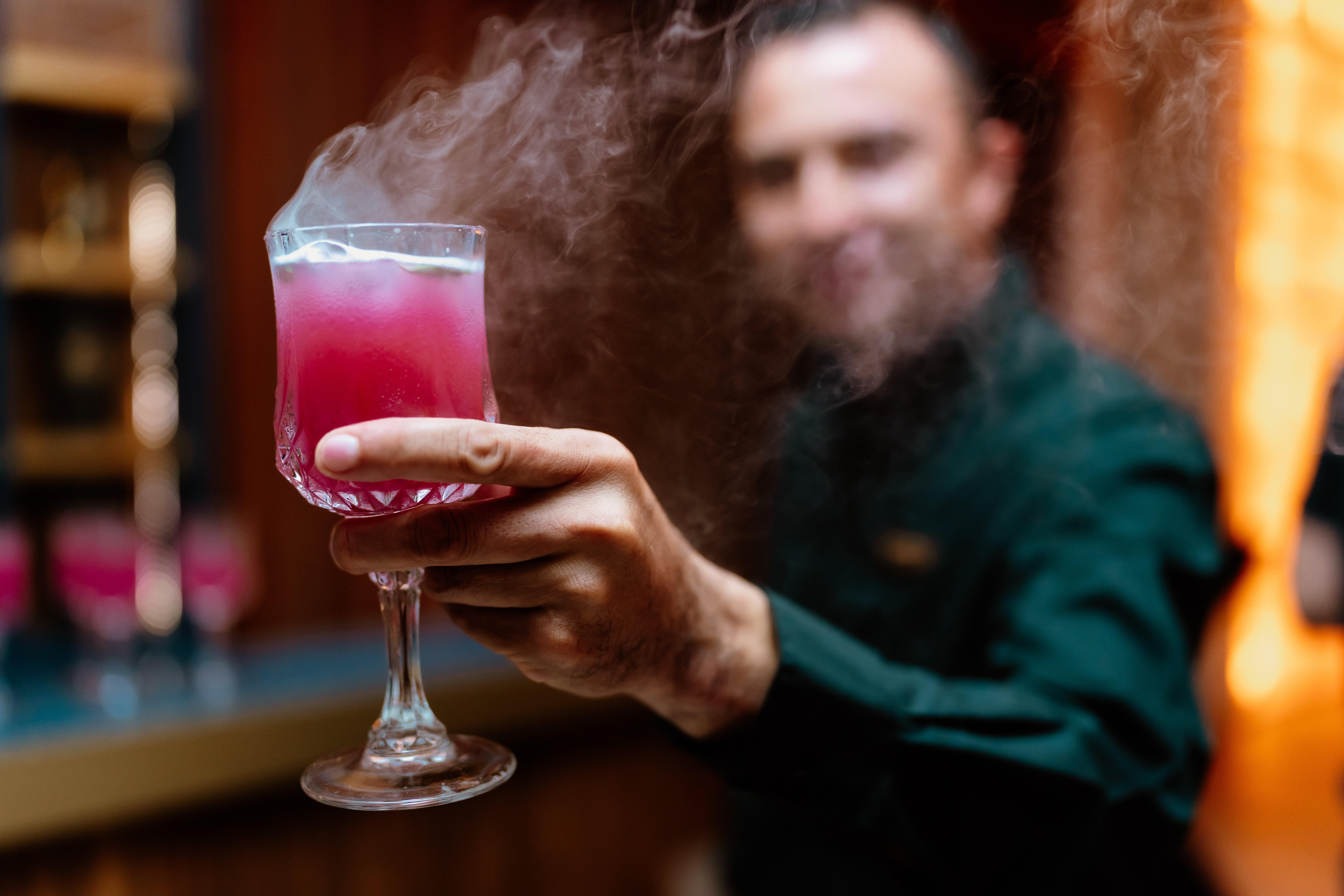 a man holding a glass with a pink drink