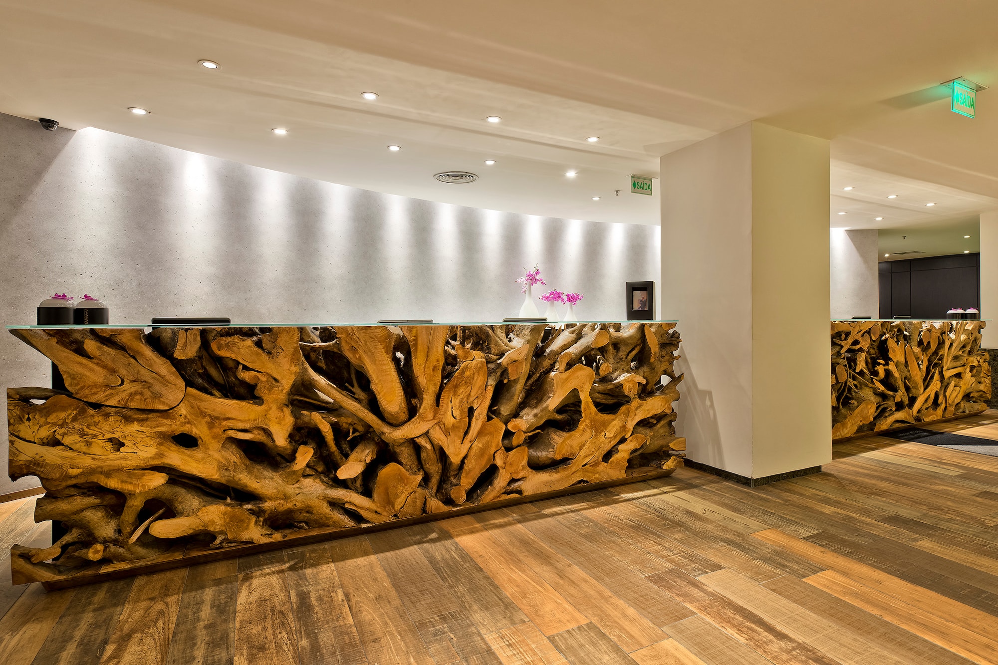 Teak wood root reception desk in a modern hotel lobby.