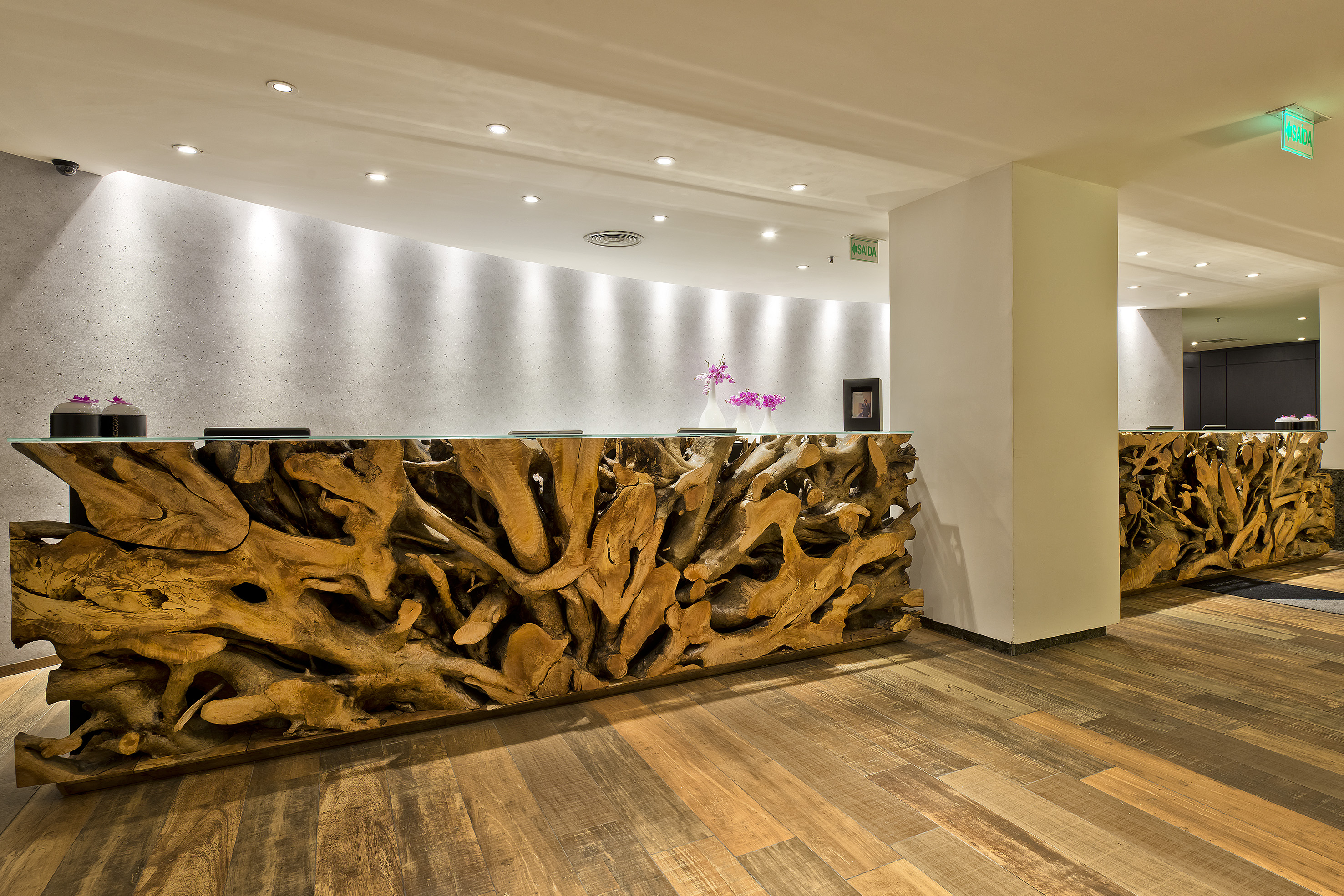 Teak wood root reception desk in a modern hotel lobby.