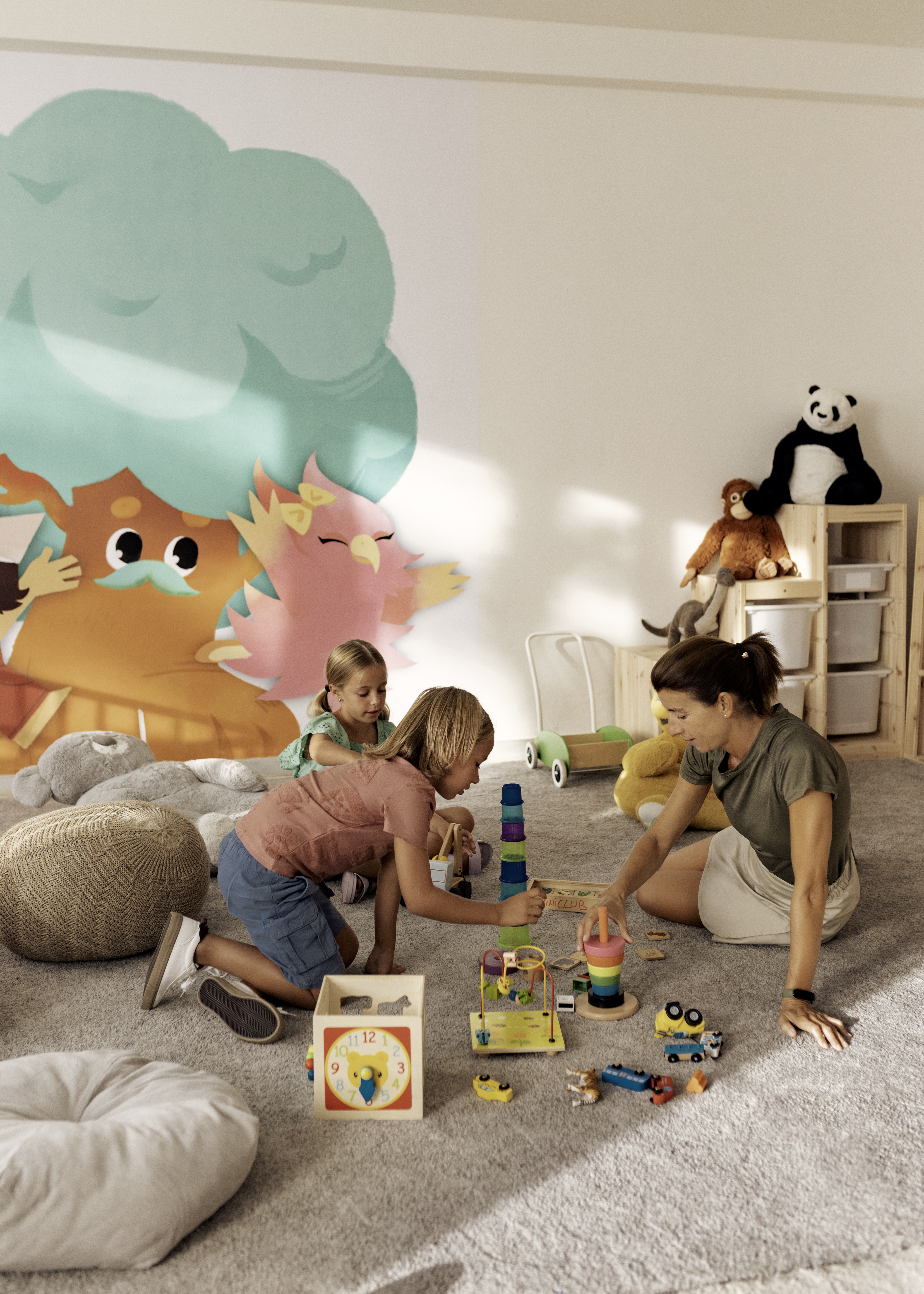 Kids and mom playing with educational toys on carpet. Bright playroom.