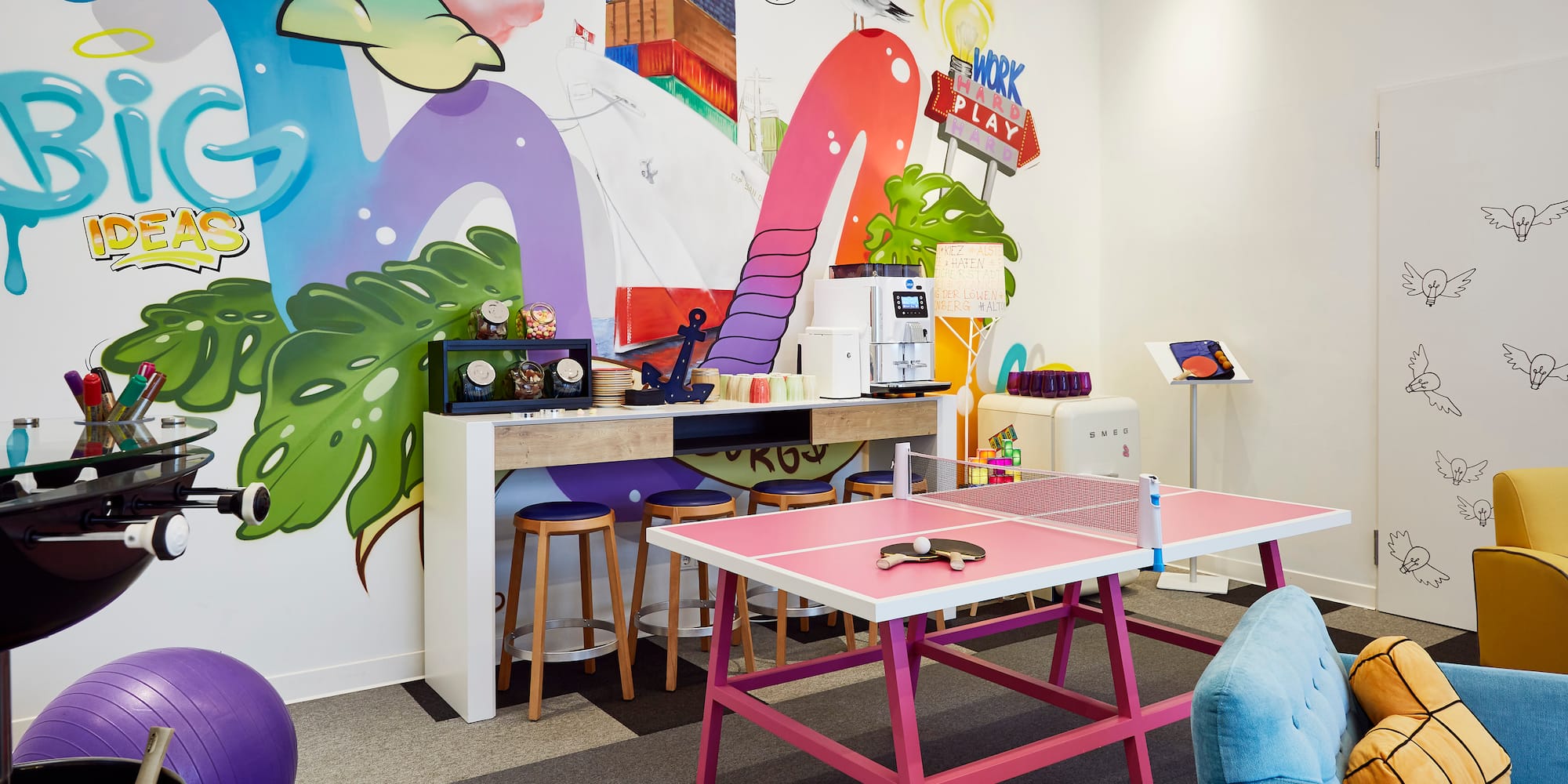 a room with a ping pong table and colorful wall art