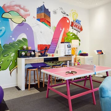 a room with a ping pong table and colorful wall art