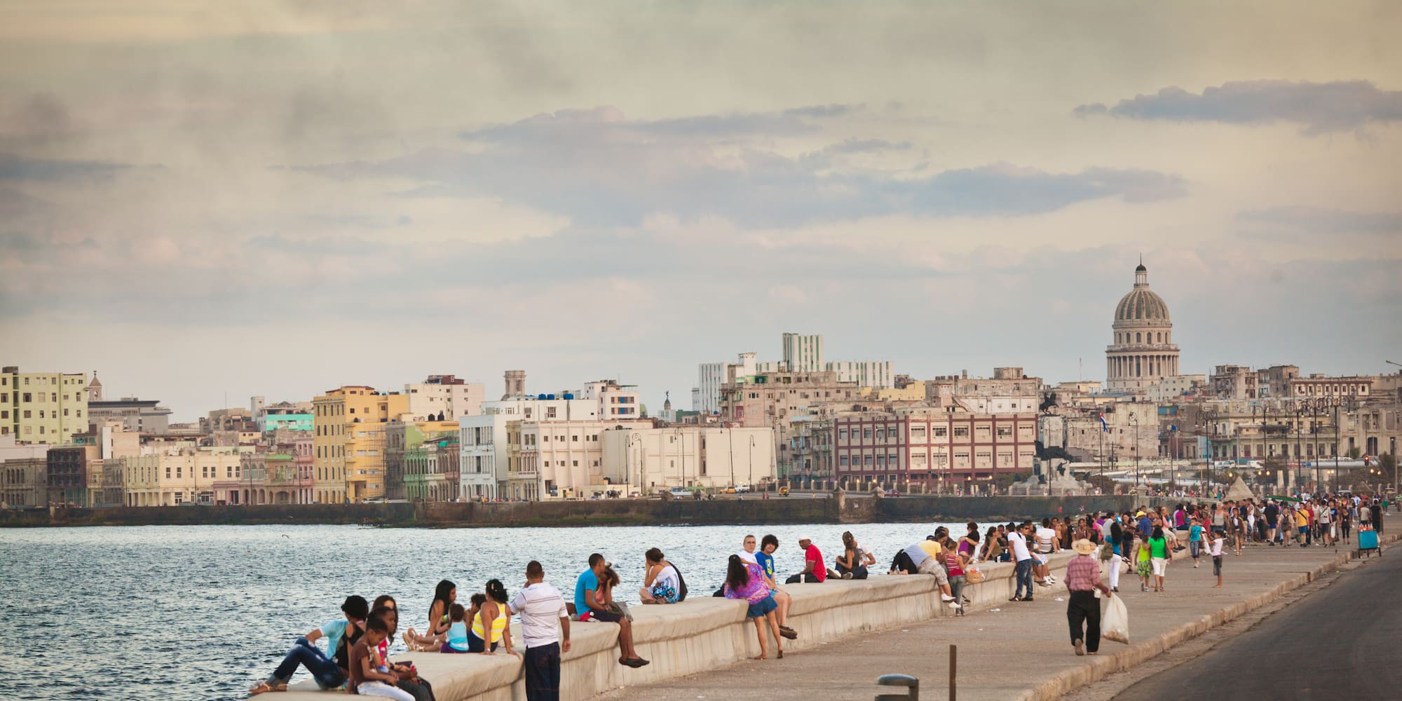 a group of people sitting on a wall next to water