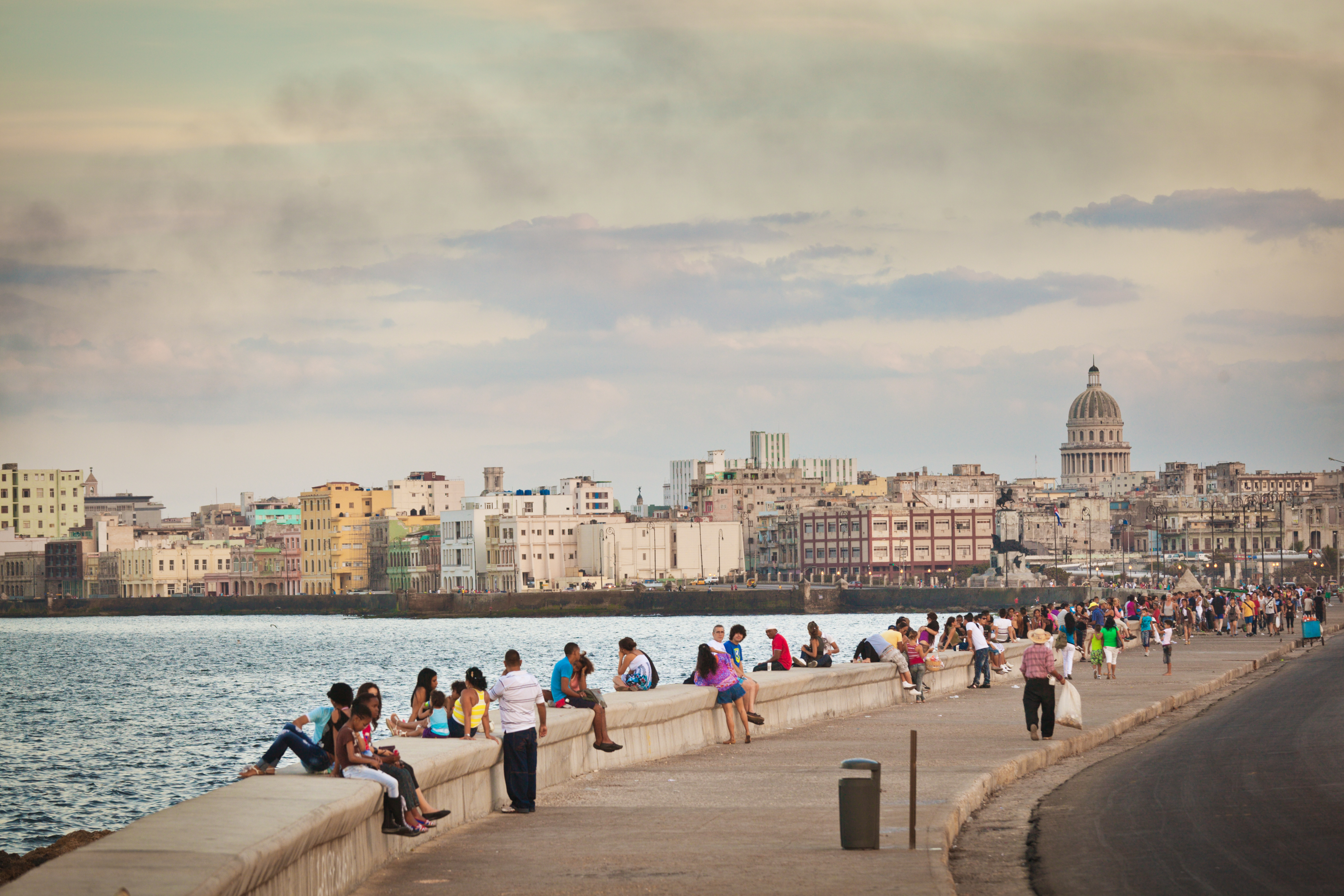 a group of people sitting on a wall next to water