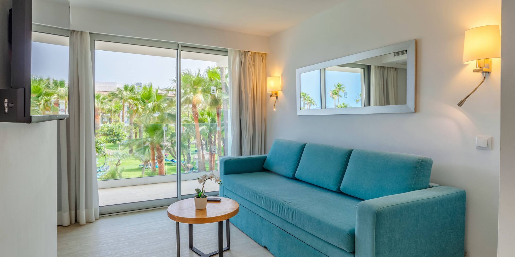 a blue couch in a room with a table and a mirror