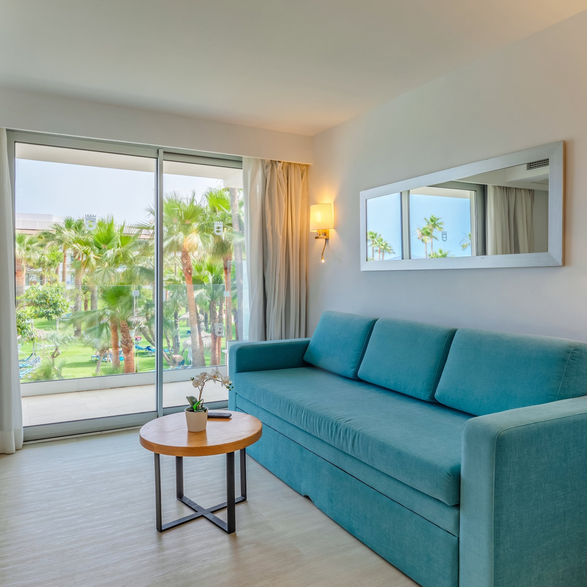 a blue couch in a room with a table and a mirror