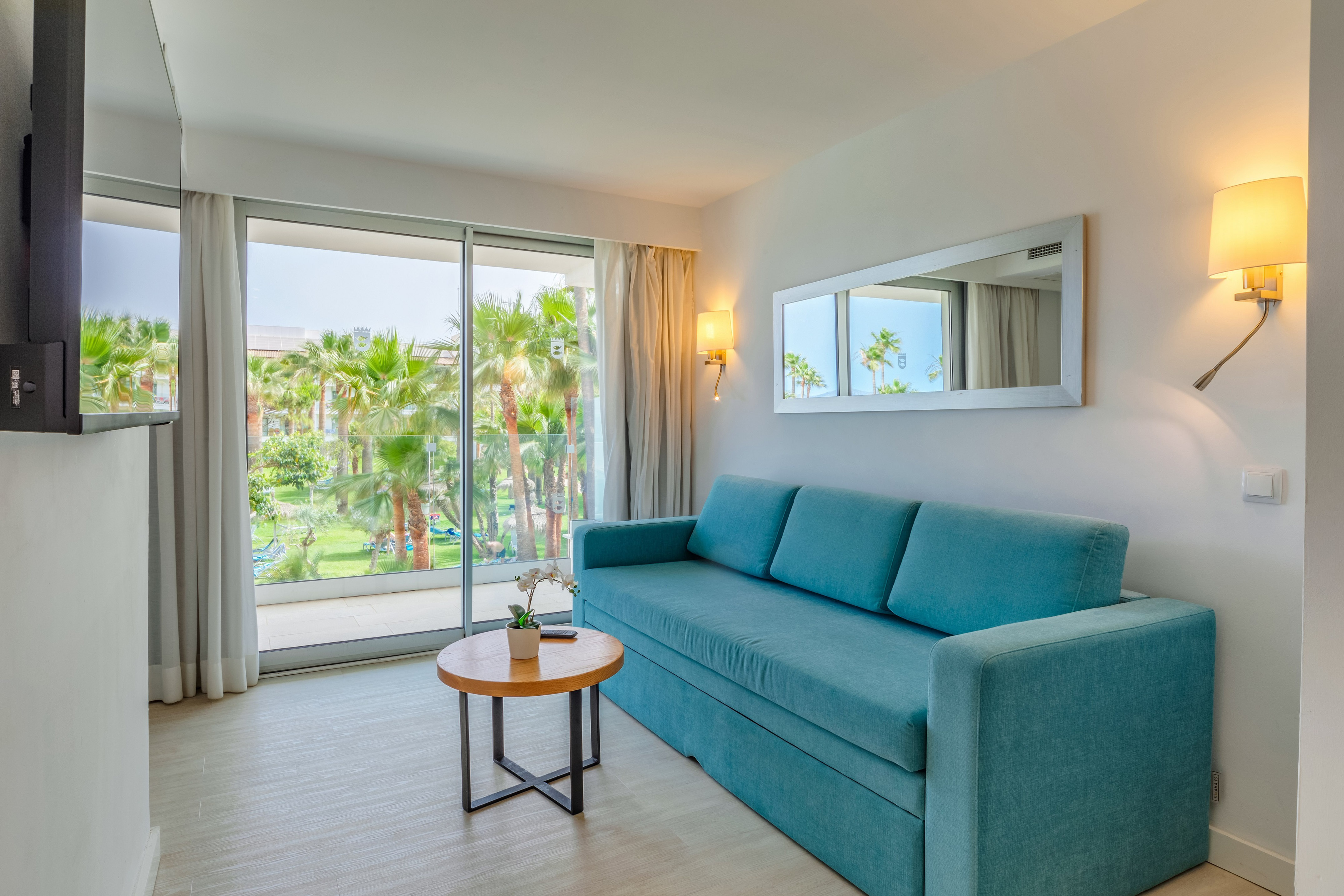 a blue couch in a room with a table and a mirror