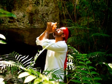 a man drinking from a bottle in the woods