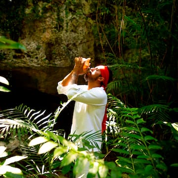 a man drinking from a bottle in the woods