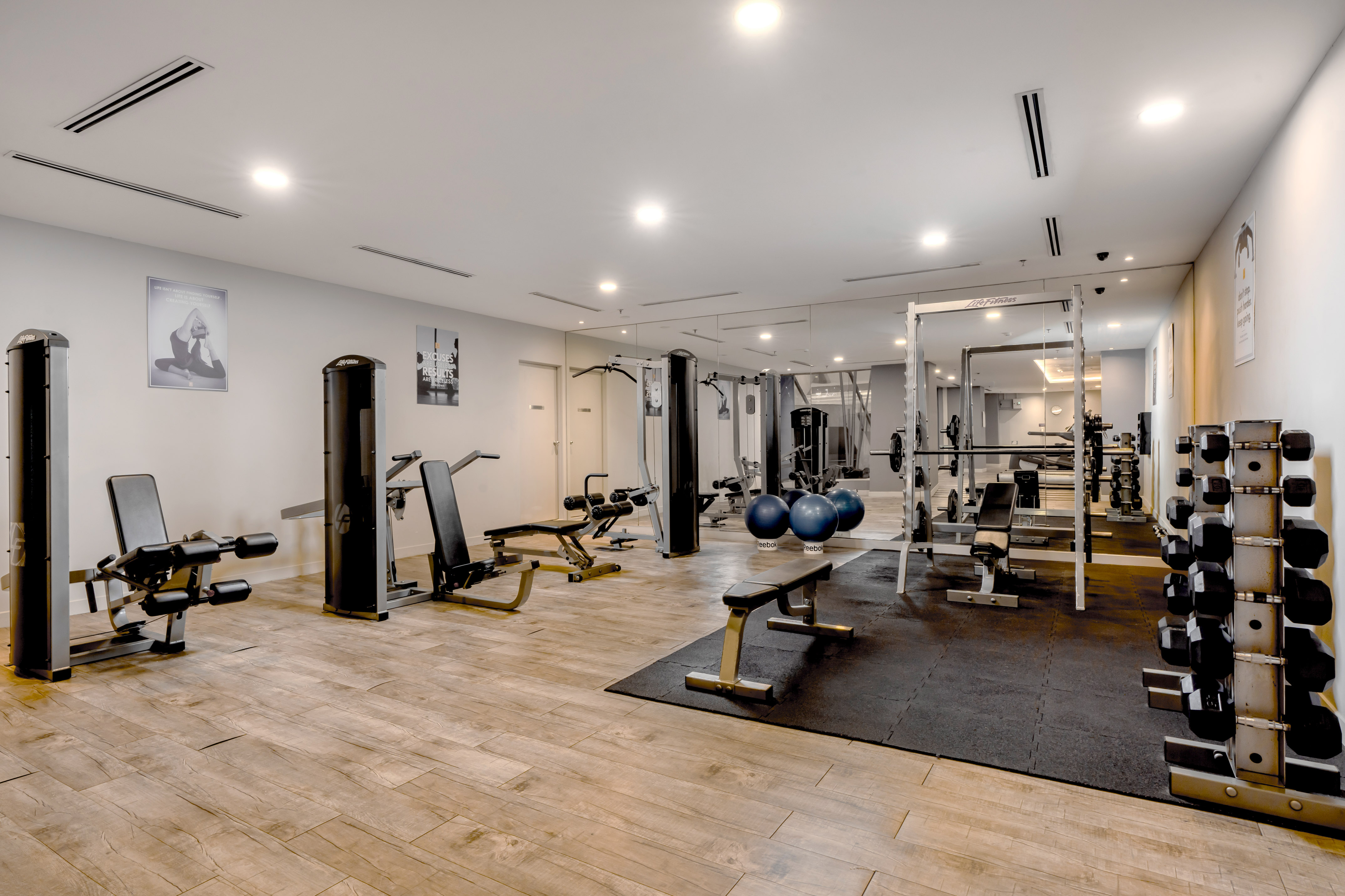 Clean, bright gym with weight machines, dumbbell rack, and exercise benches.