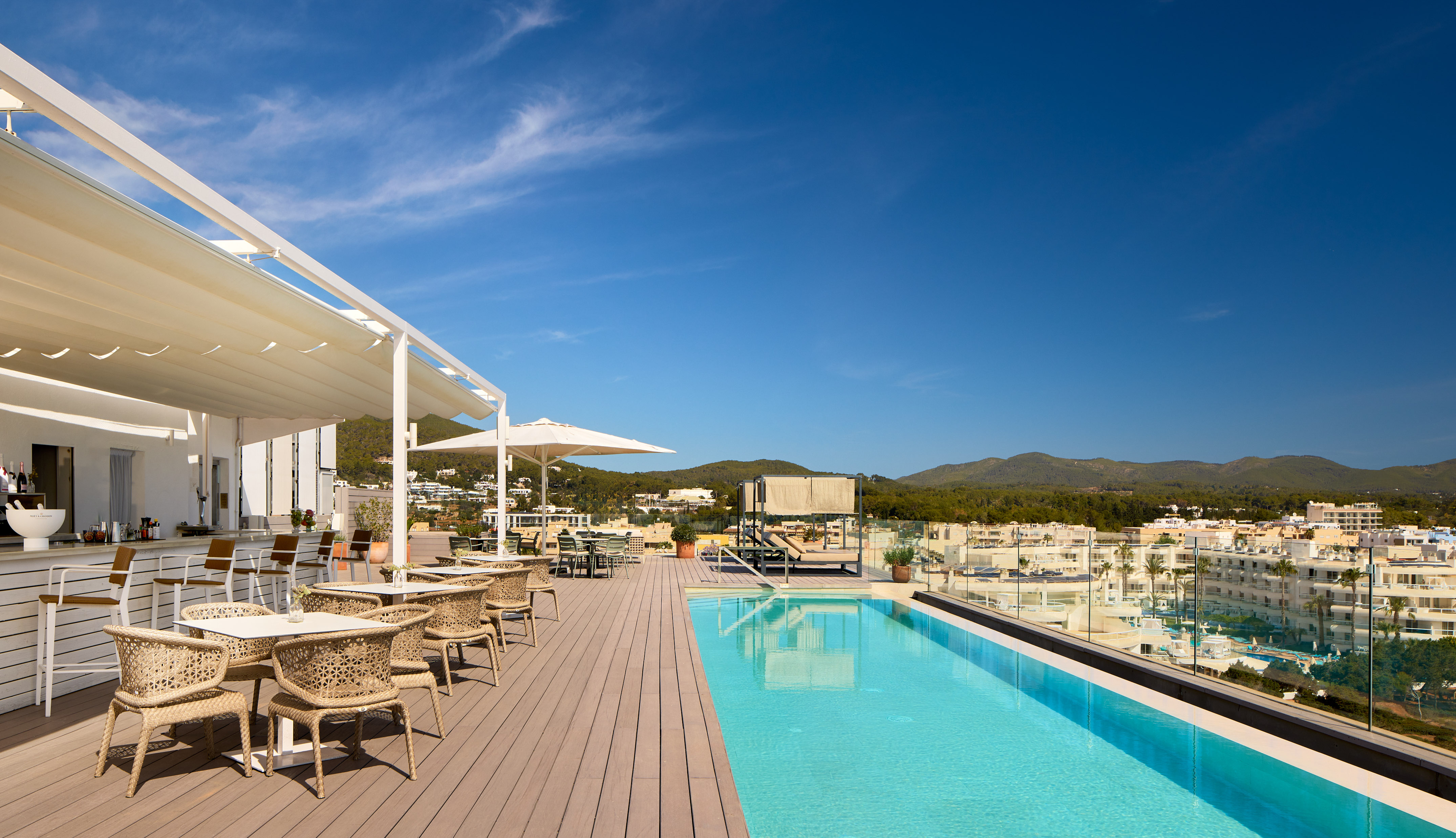 Rooftop pool, bar, and dining terrace with scenic town and mountain views.