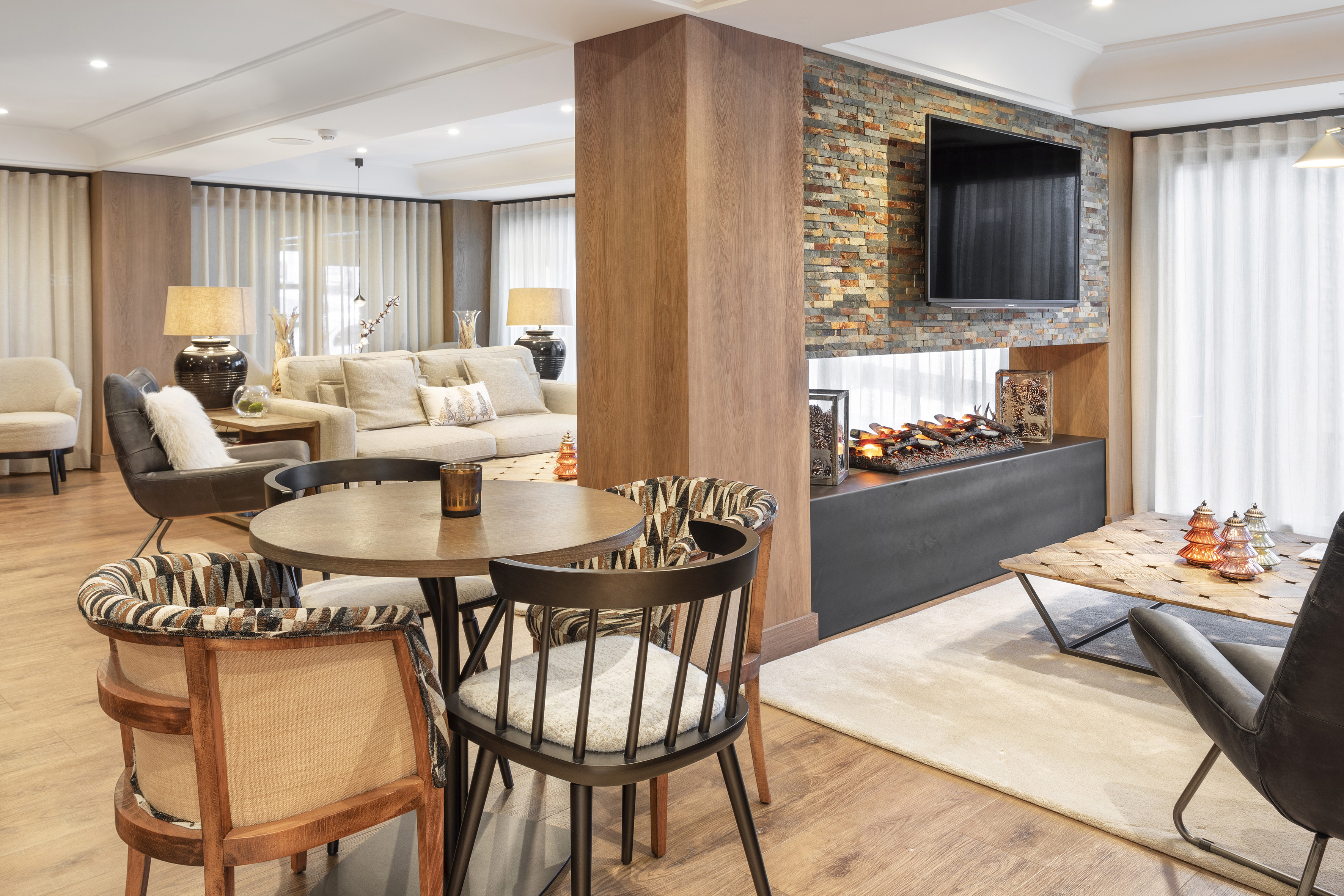 Cozy lounge with stone fireplace, mounted TV, warm wood, and comfortable seating.