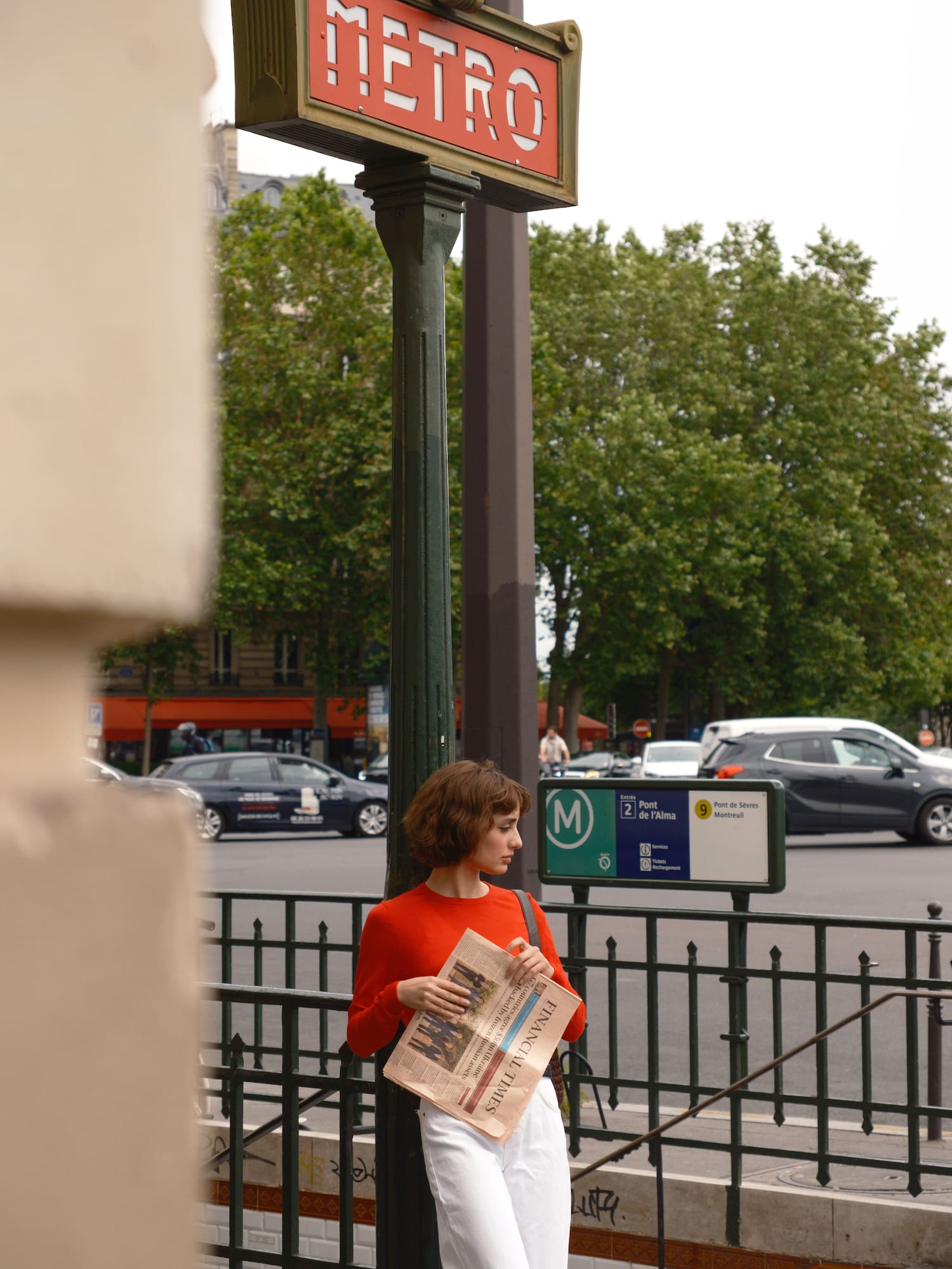 a woman standing on a sidewalk holding a newspaper