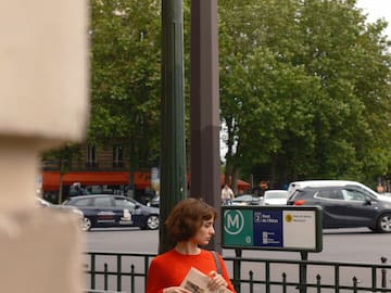a woman standing on a sidewalk holding a newspaper