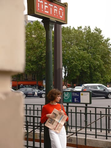 a woman standing on a sidewalk holding a newspaper