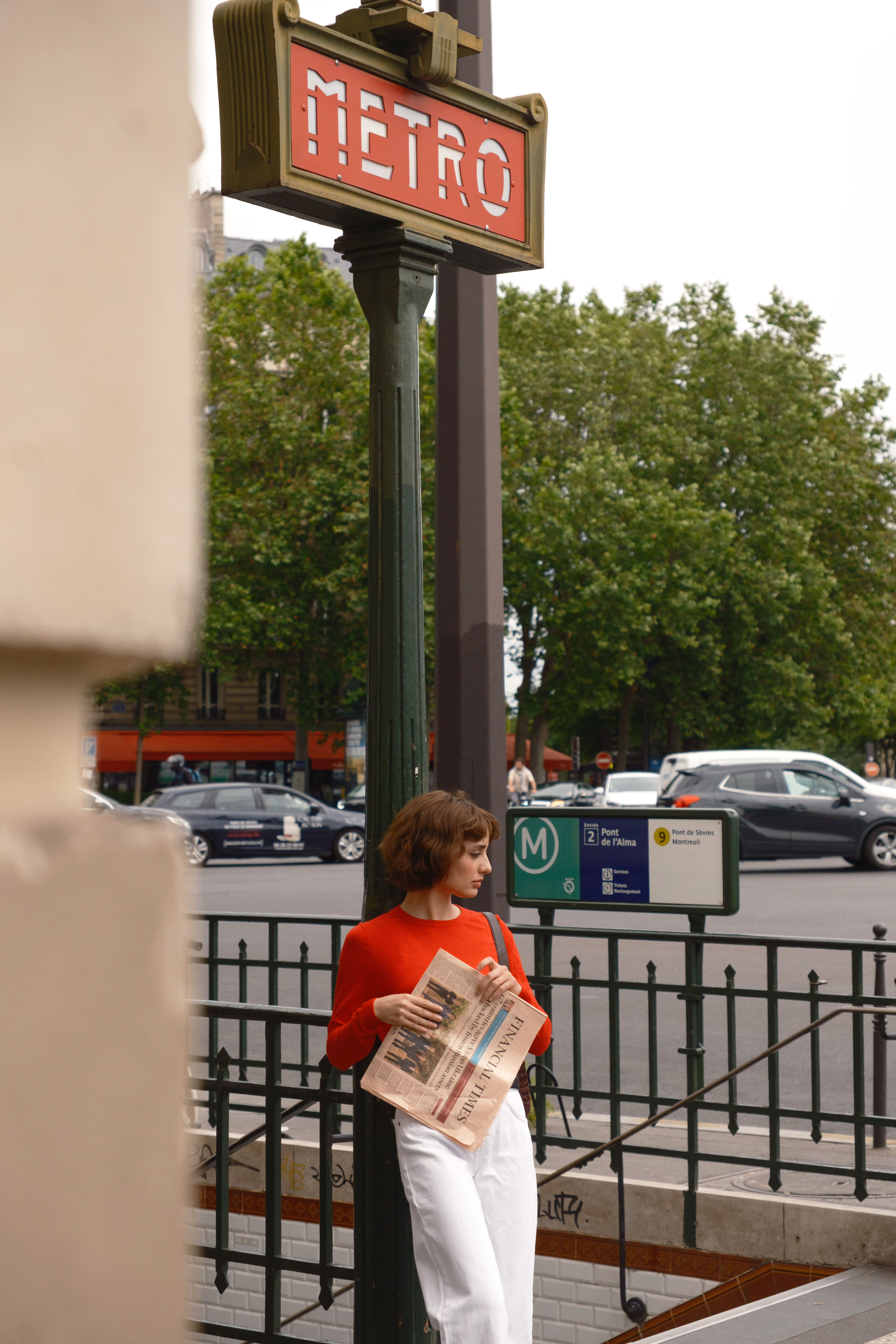 Woman reading Financial Times at vintage Paris Metro station.
