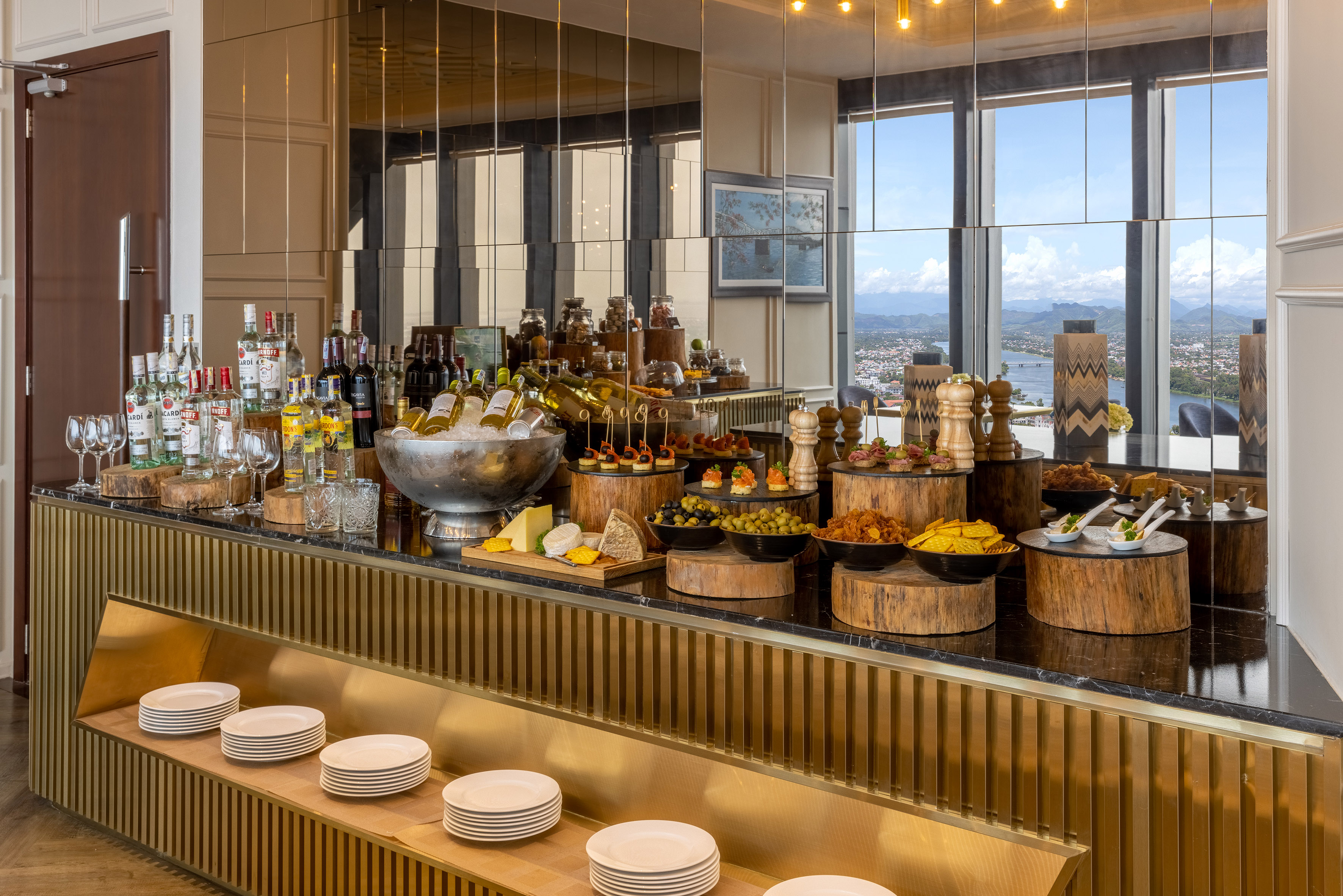 Upscale buffet bar with drinks, canapés, cheese, and a scenic city-river view.
