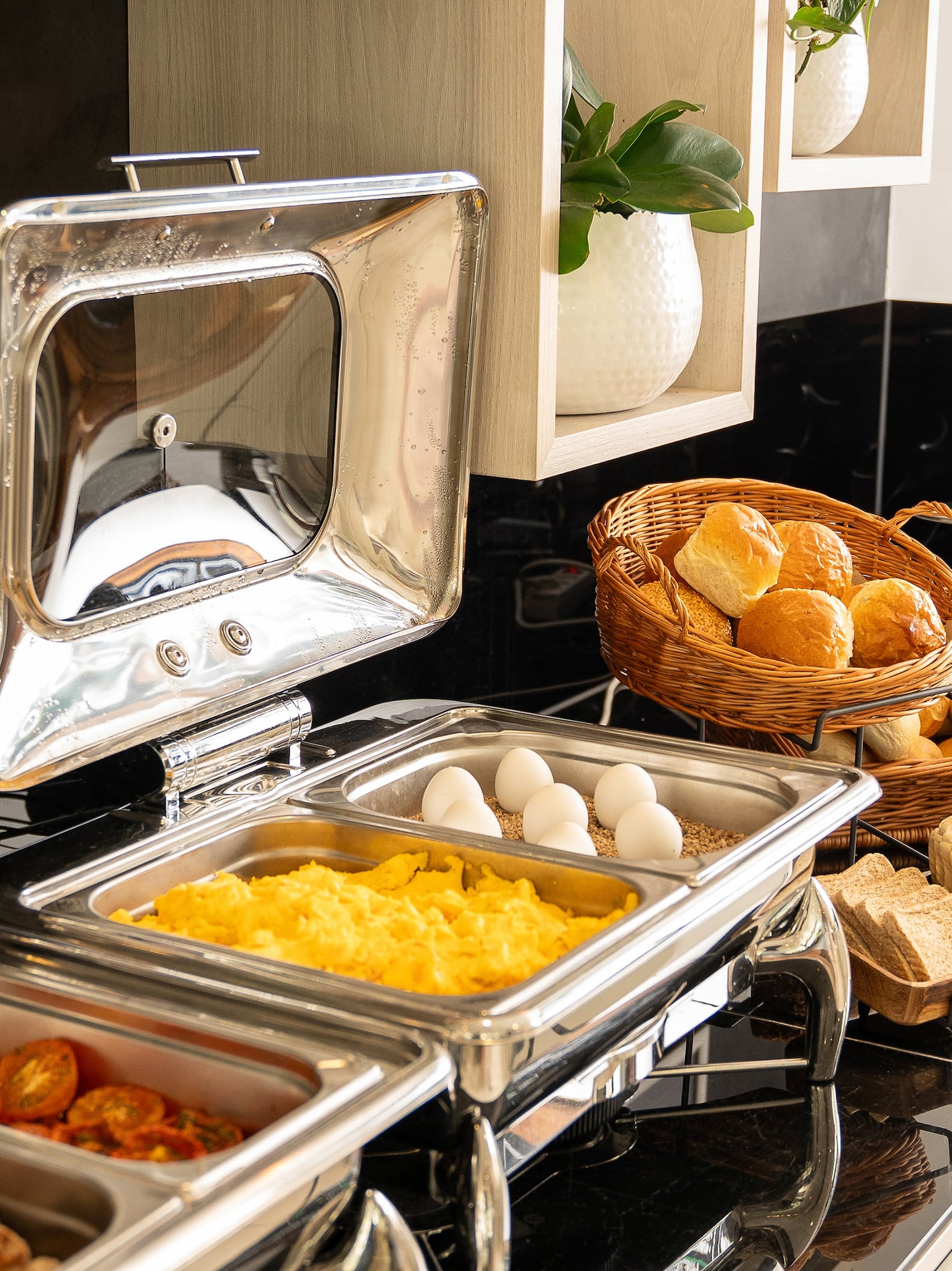 Hotel breakfast buffet featuring scrambled eggs, bread, toast, and hot food.