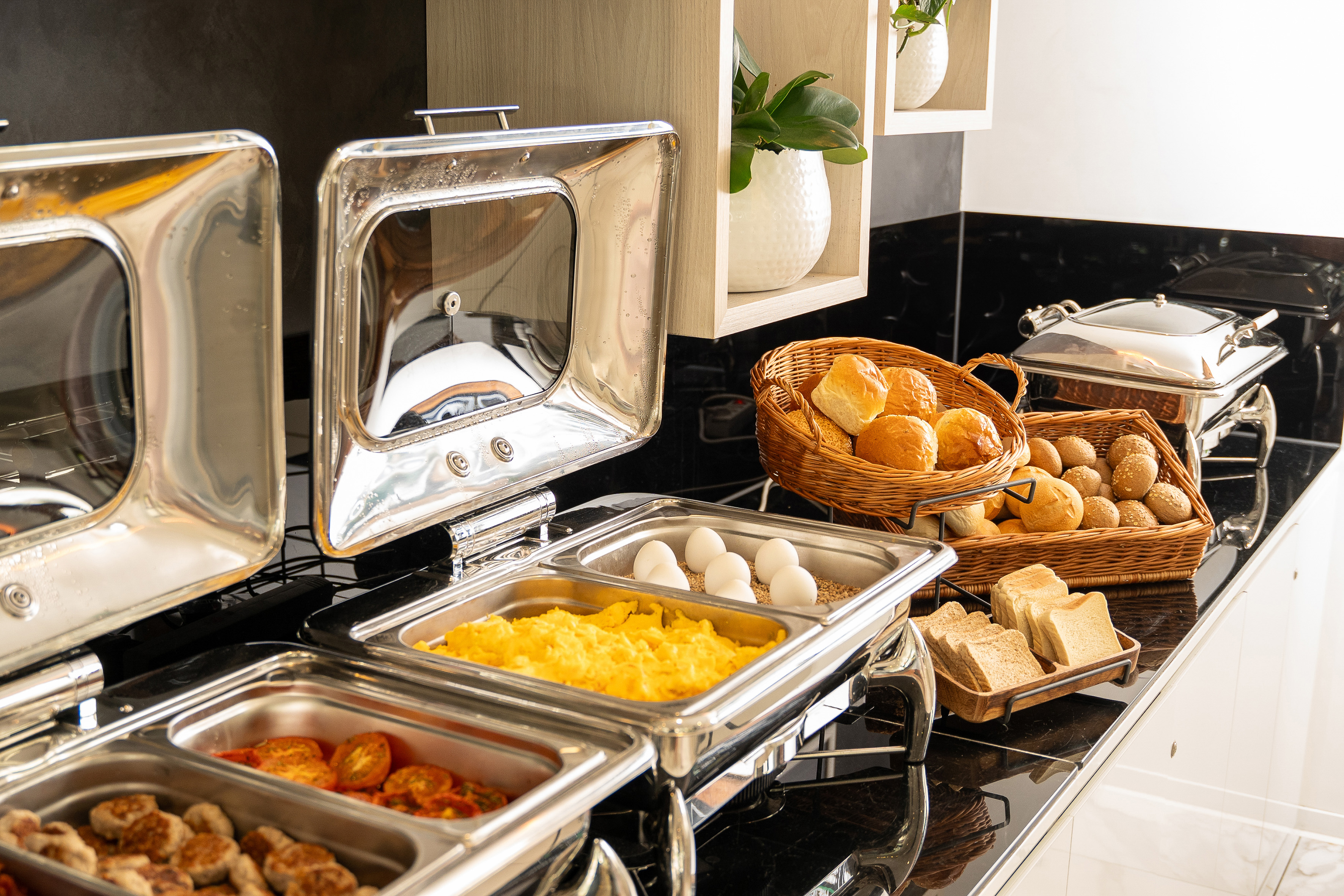 Breakfast buffet with scrambled eggs, assorted bread, and hot food.