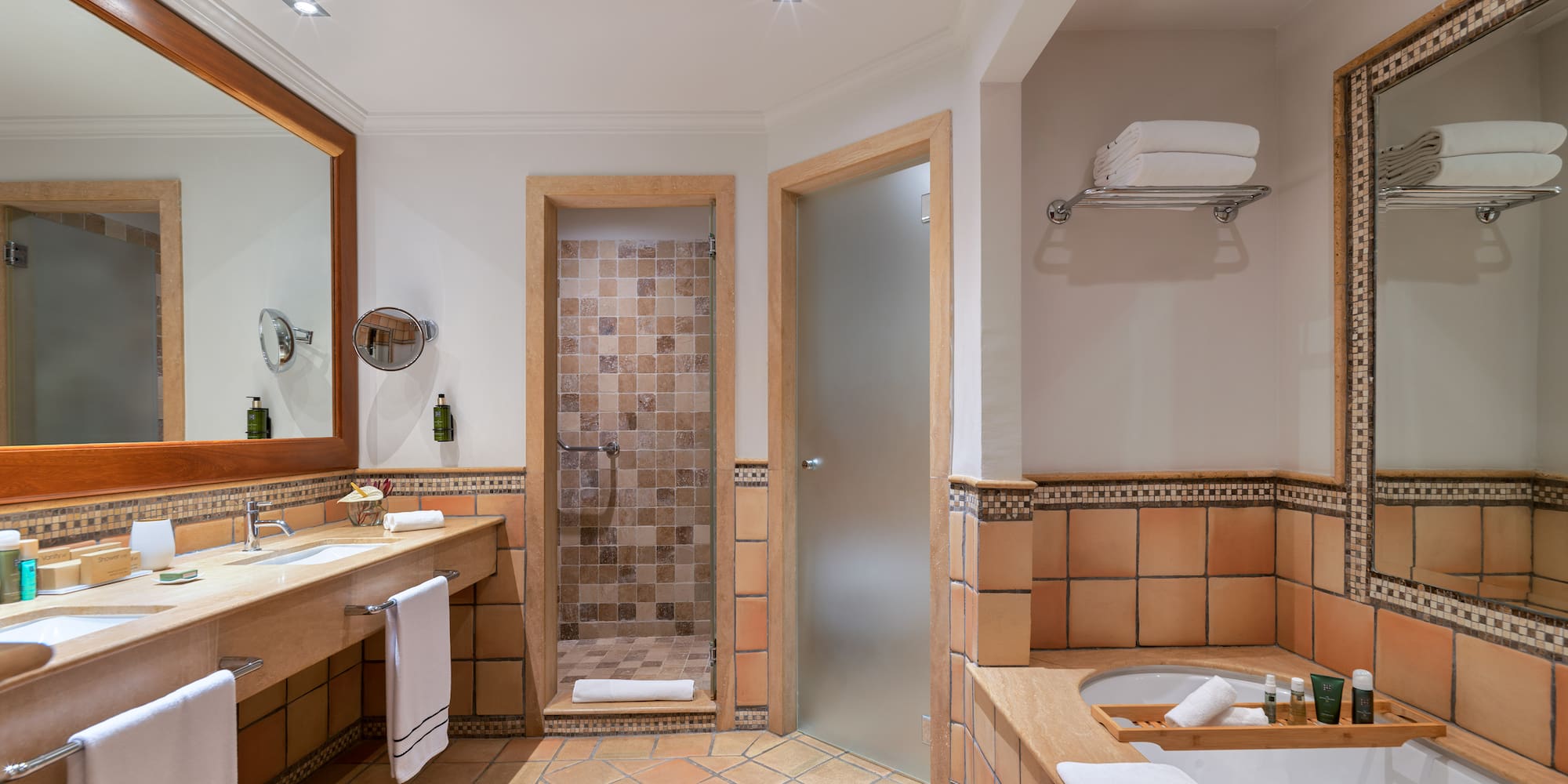 Terracotta tiled bathroom with double vanity, walk-in shower, and bathtub.