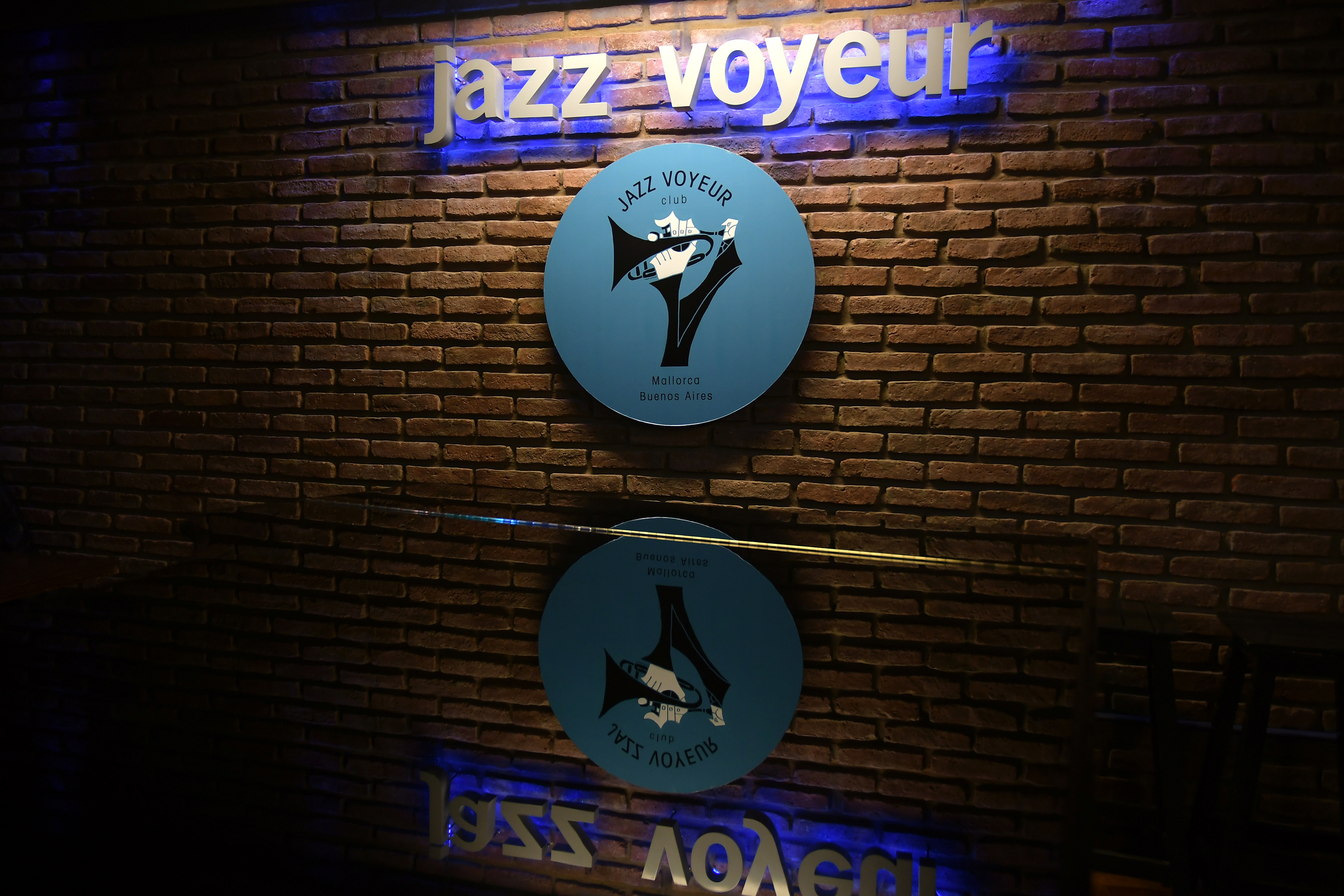 Jazz Voyeur club sign on a brick wall with blue neon light. Mallorca, Buenos Aires.