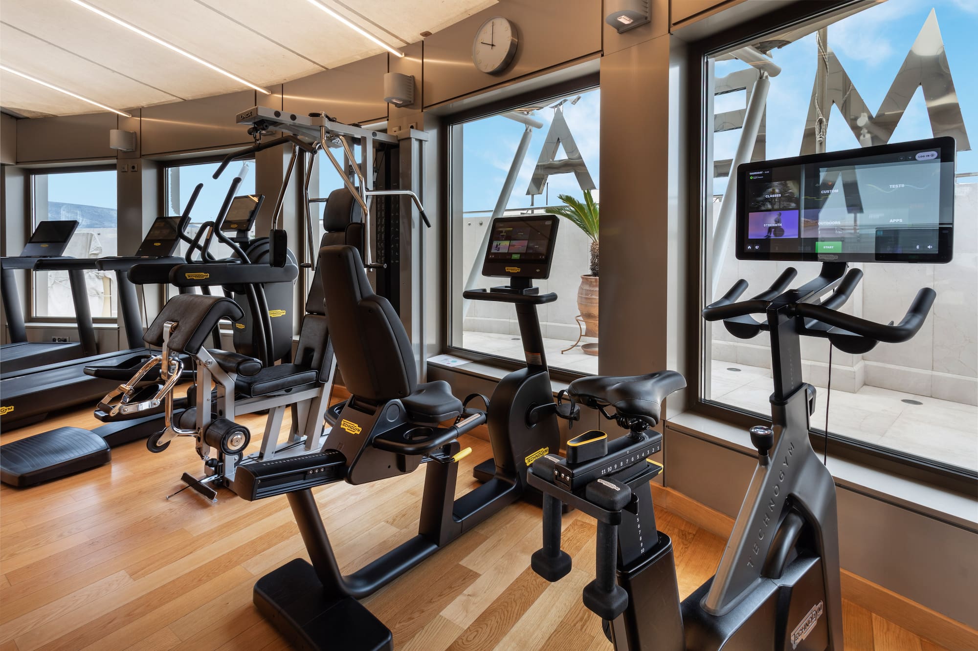 Modern Technogym fitness center with treadmills, exercise bikes, and large windows.