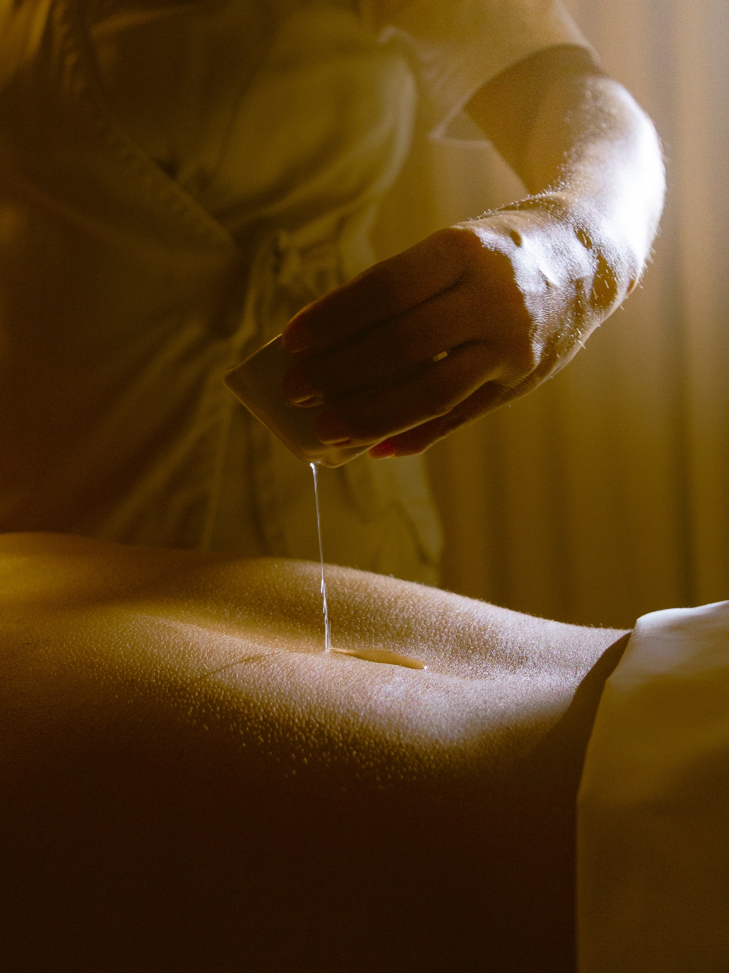a person pouring a liquid onto a person's back