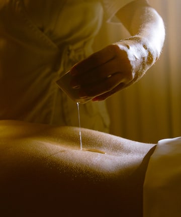a person pouring a liquid onto a person's back