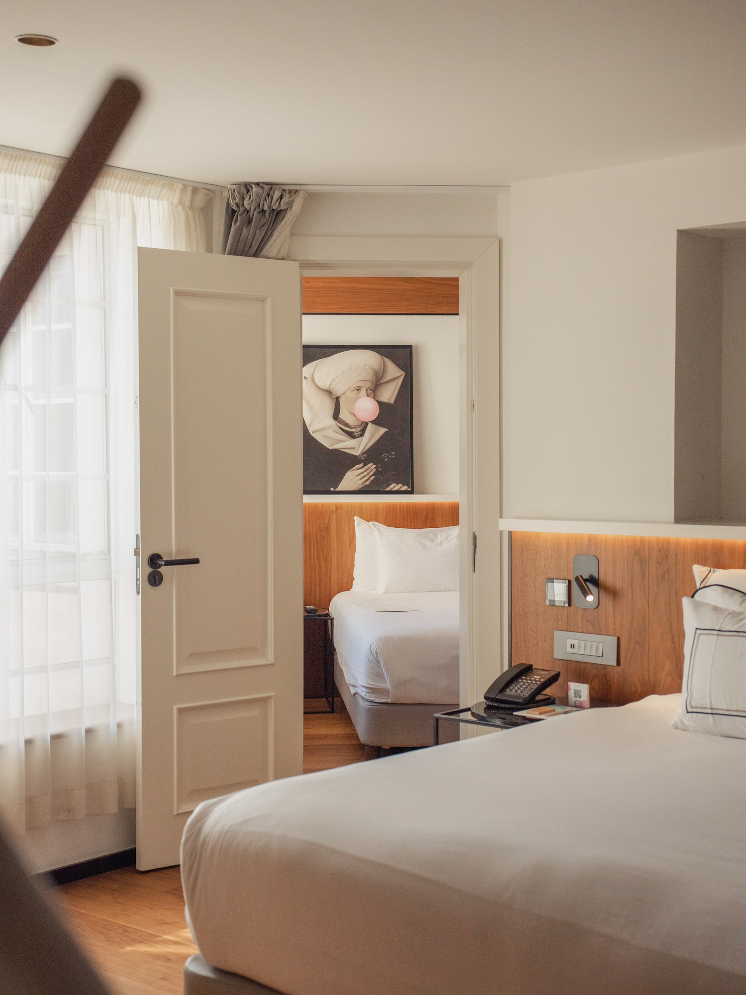 Modern hotel room with two beds, connecting door, and unique bubblegum art.