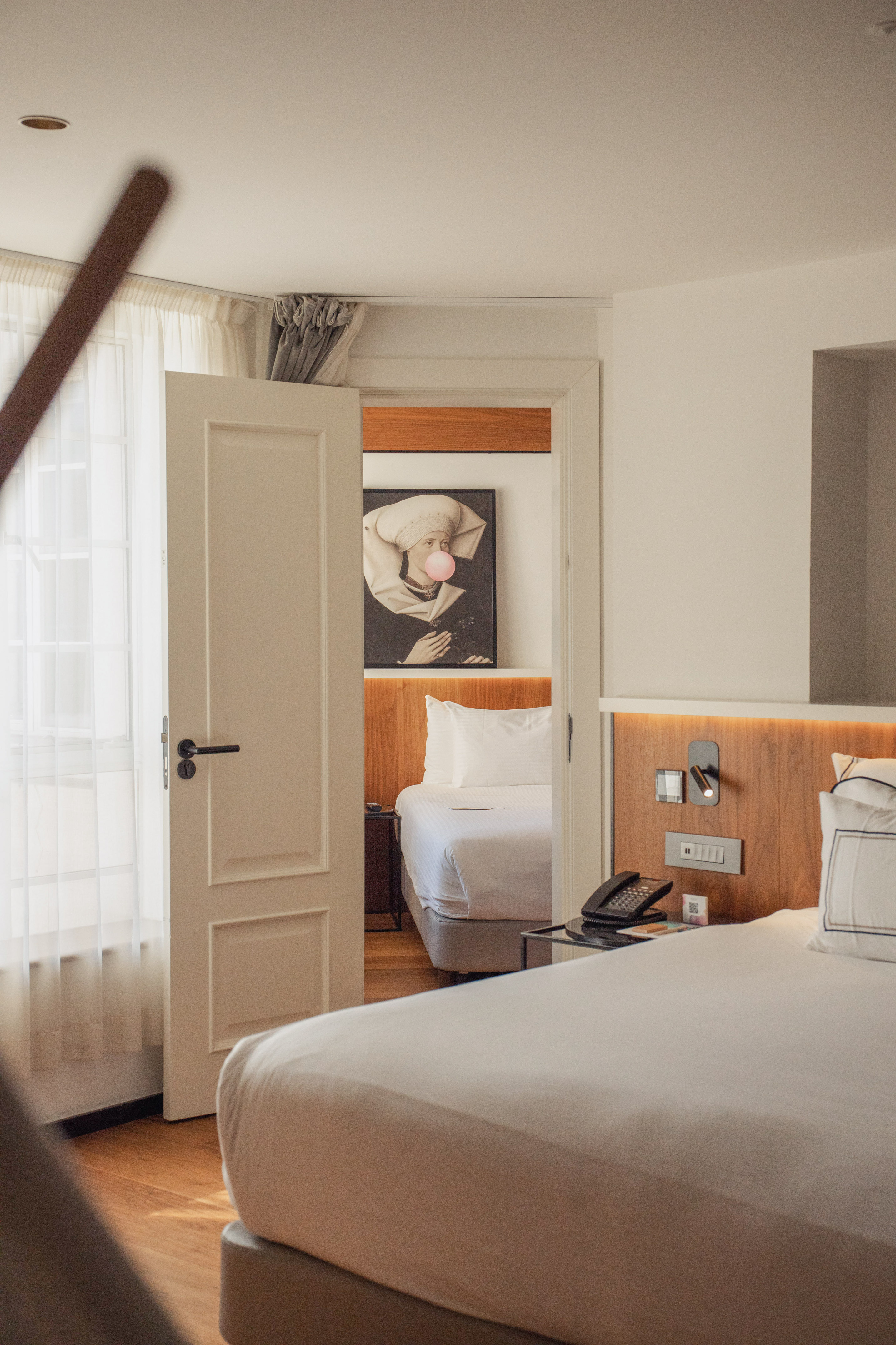Modern hotel room with two beds, connecting door, and unique bubblegum art.