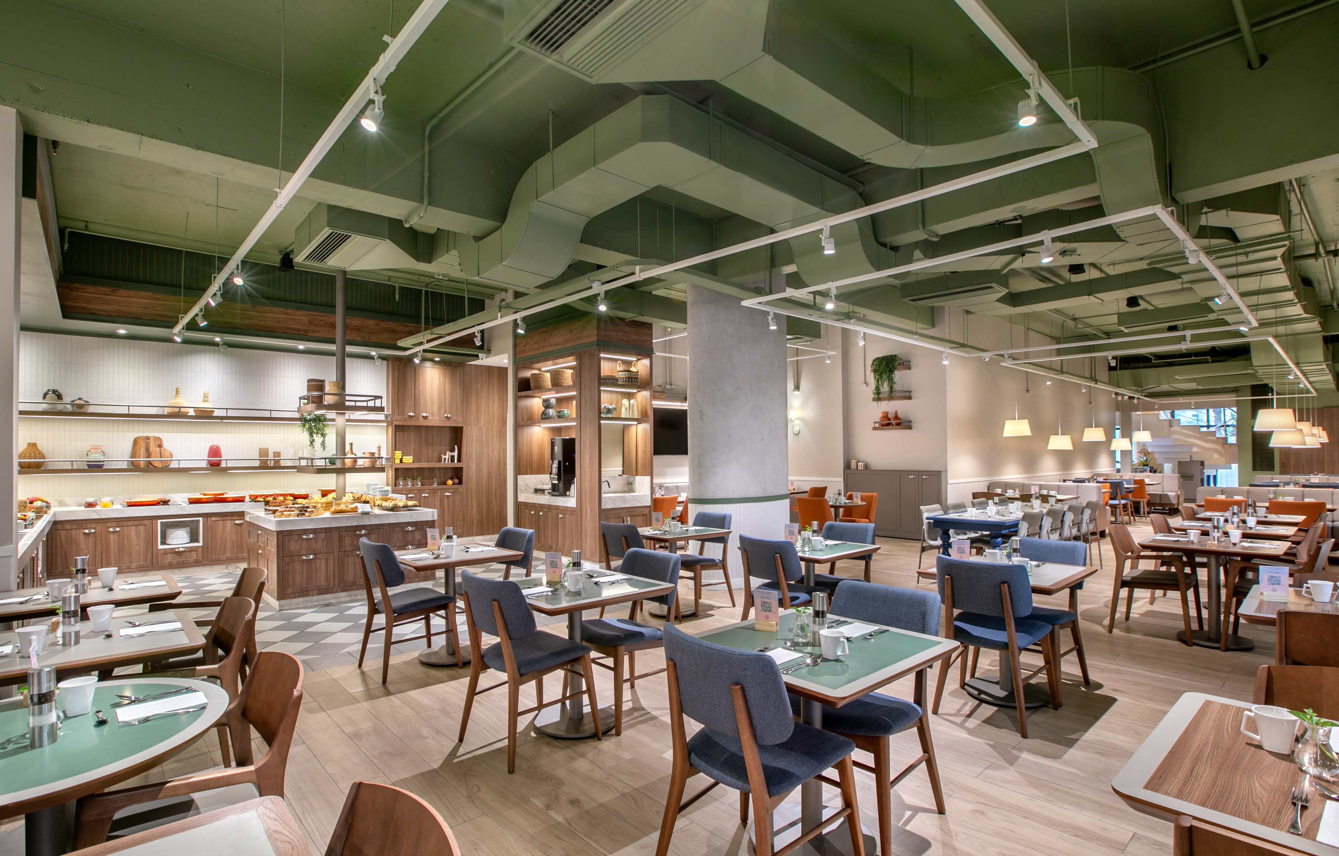 Modern restaurant with buffet, contemporary dining tables, and green ceiling.
