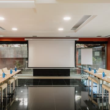 a room with a projector screen and tables