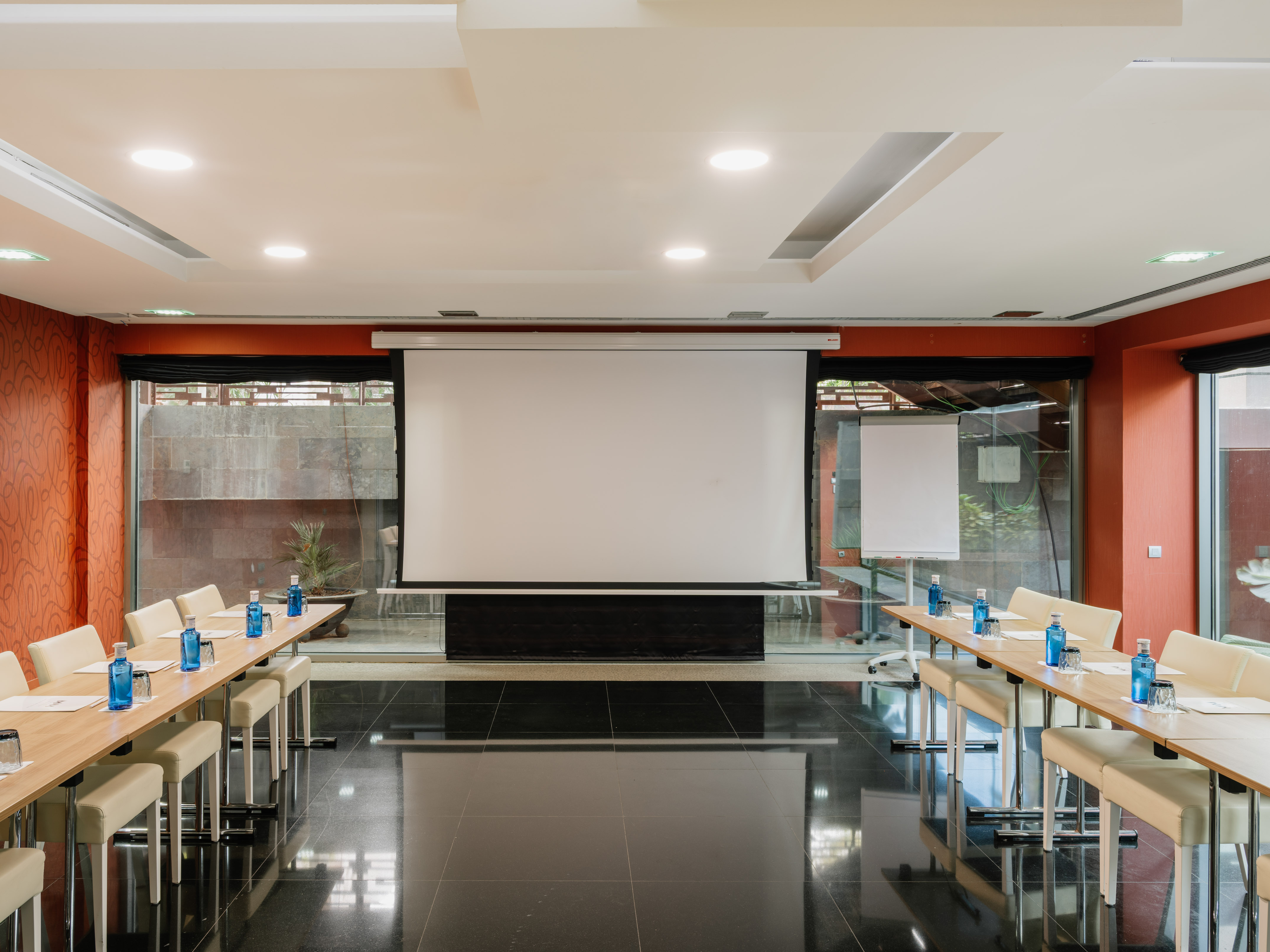 Modern business meeting room with projector screen and U-shaped tables.