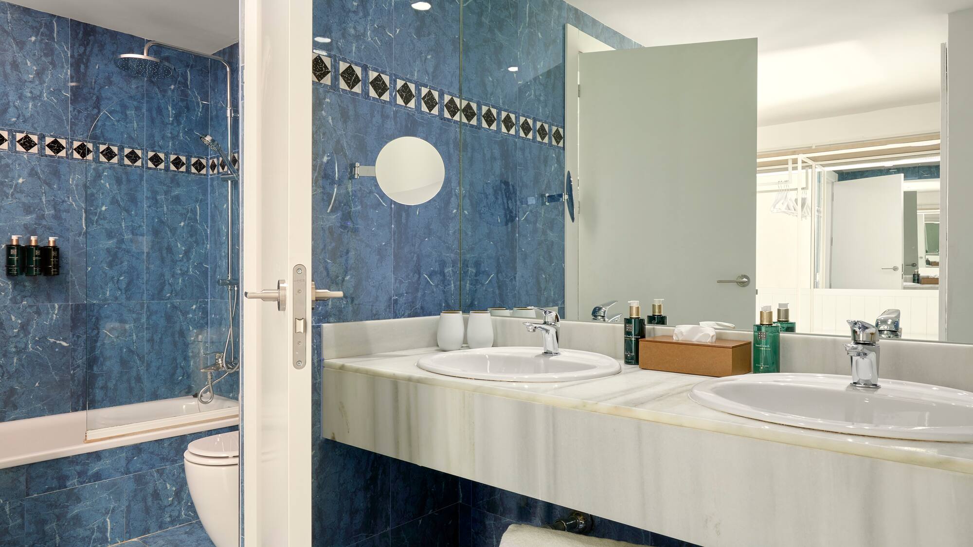 a bathroom with blue tile walls and sinks