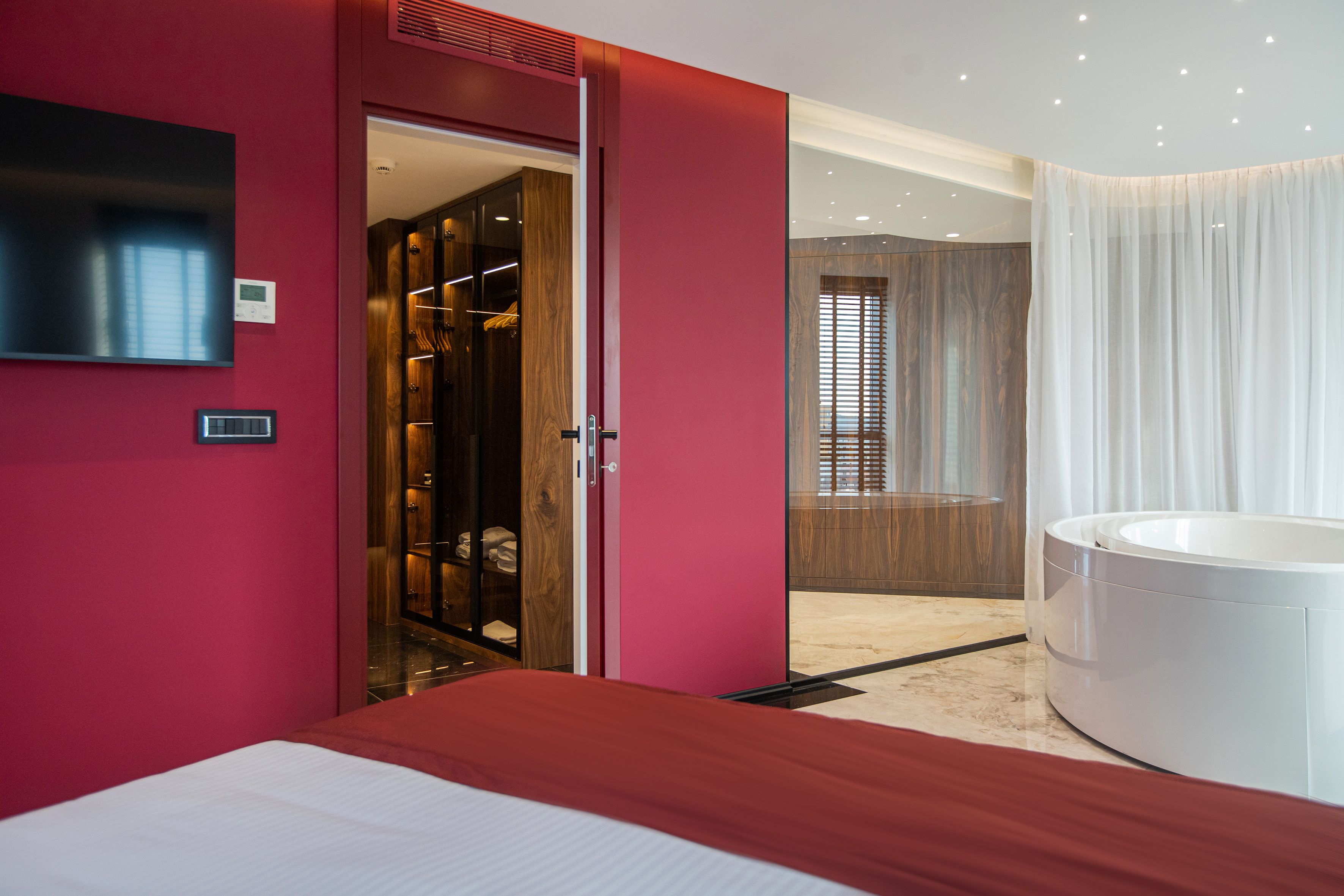 Luxury red bedroom with walk-in closet and ensuite jacuzzi.