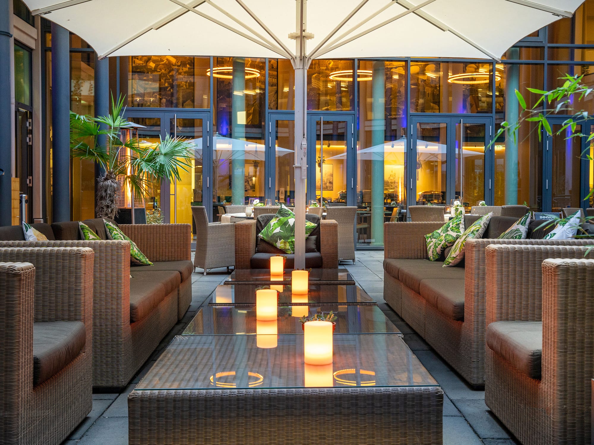 Hotel patio lounge with wicker furniture, glowing candles, and evening ambiance.