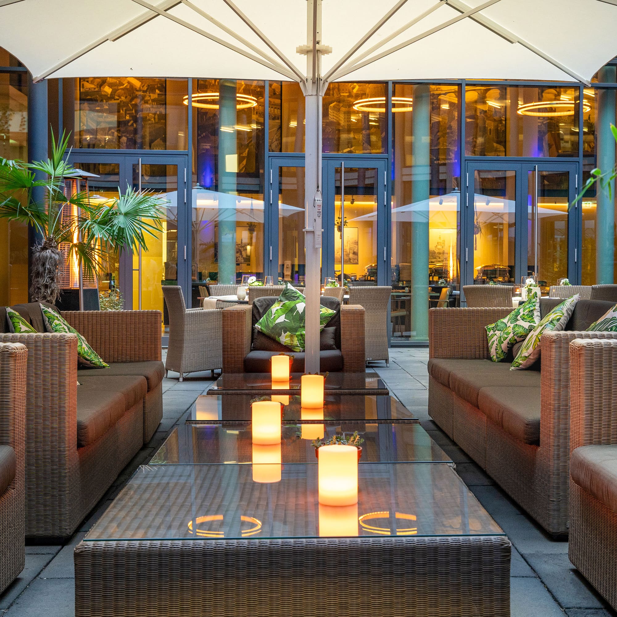 Hotel patio lounge with wicker furniture, glowing candles, and evening ambiance.