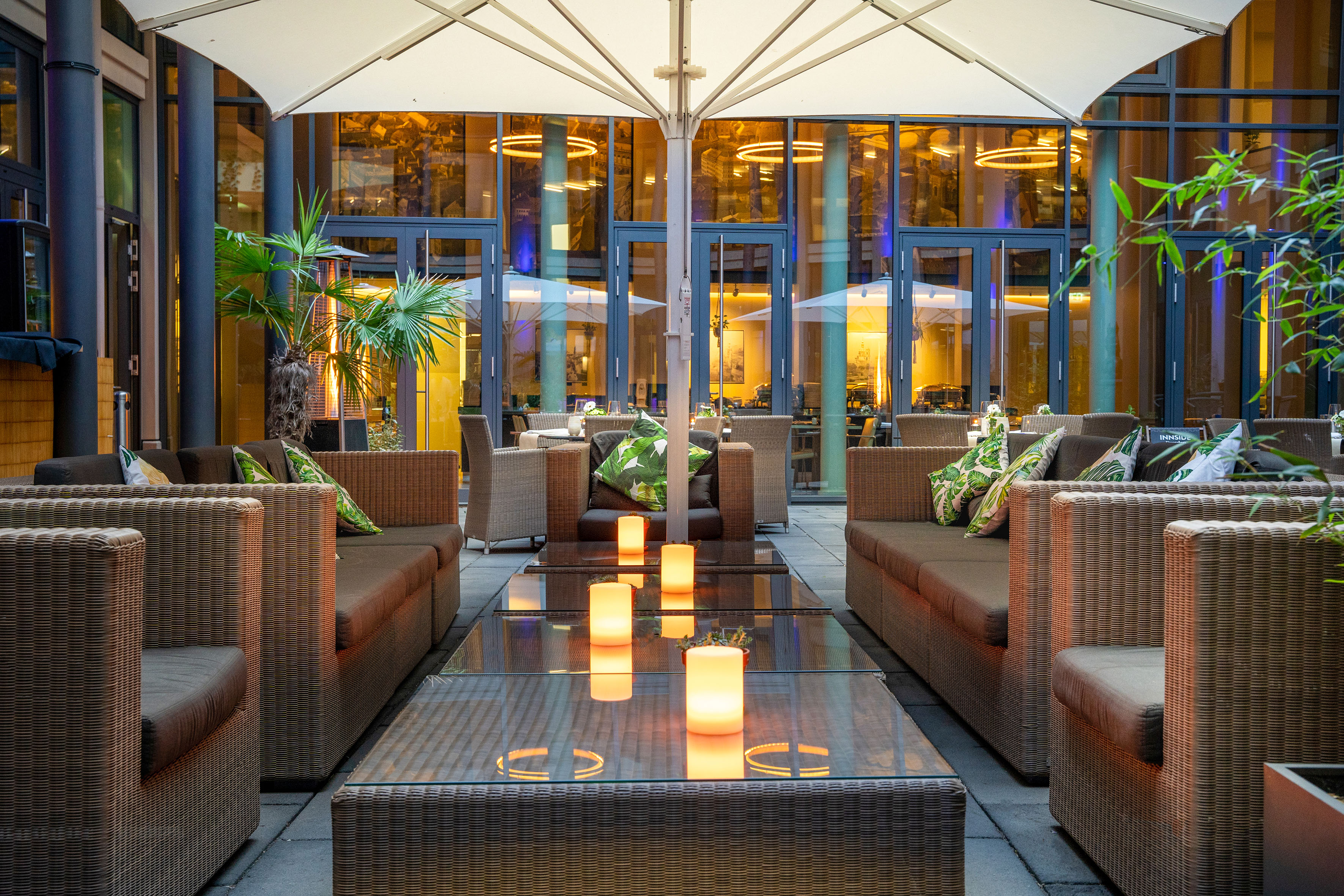 Hotel patio lounge with wicker furniture, glowing candles, and evening ambiance.