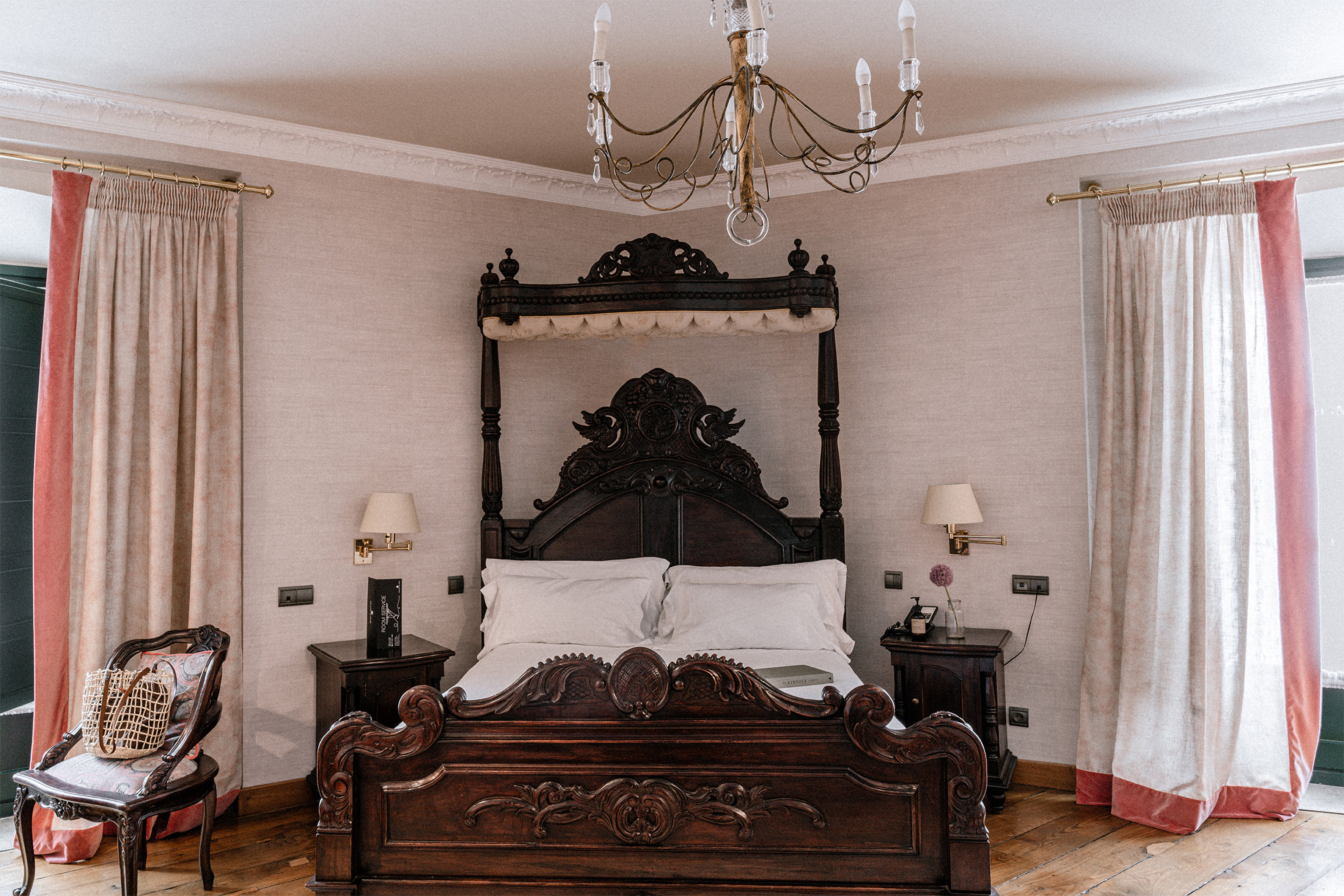 Ornate dark wood four-poster bed in a traditional, elegant hotel bedroom.
