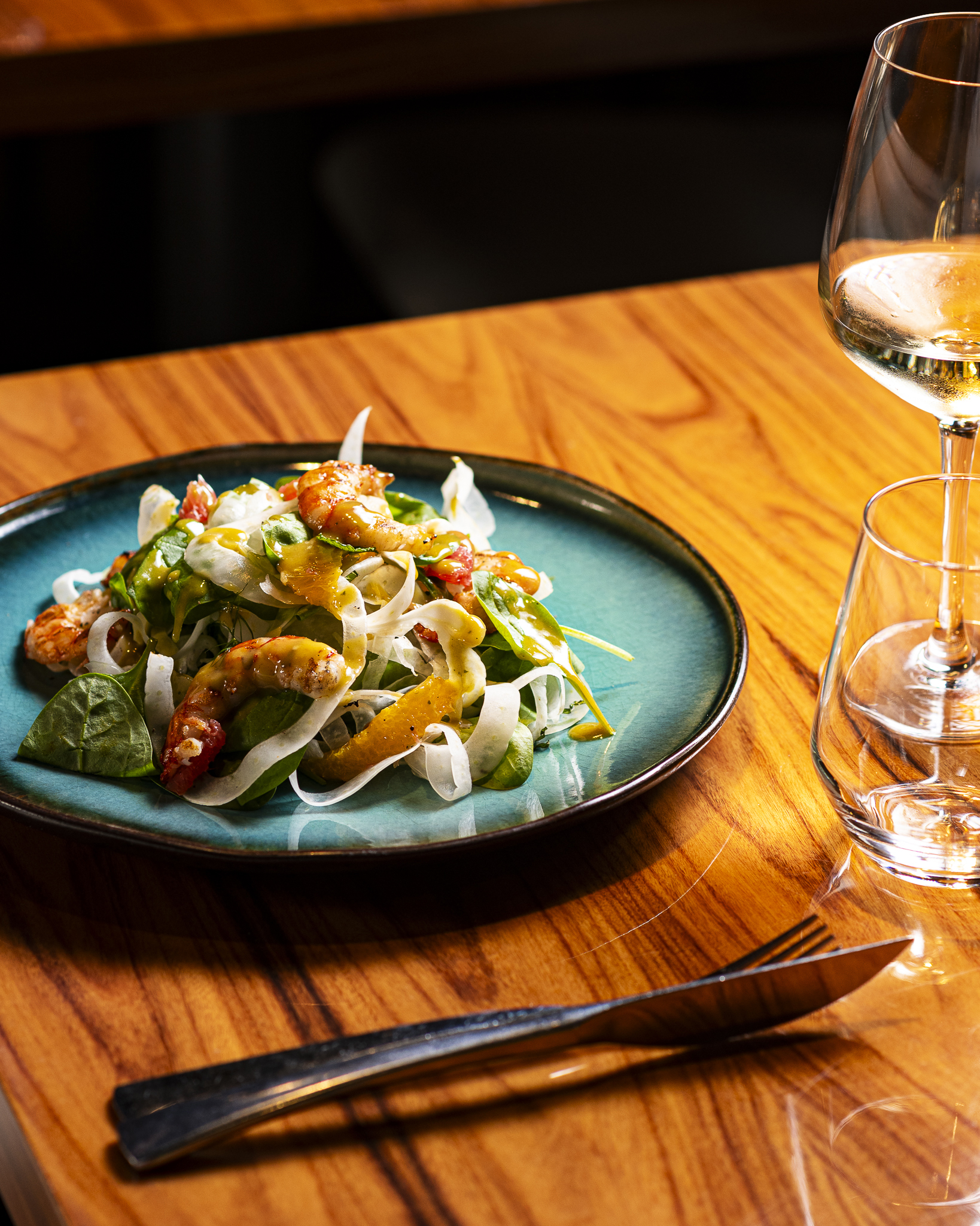 Shrimp and fennel salad on a teal plate with citrus dressing; white wine.