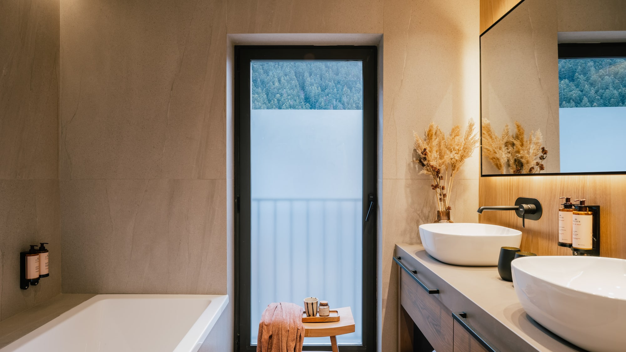 Luxury spa bathroom with forest view, double vanity, and soaking tub.