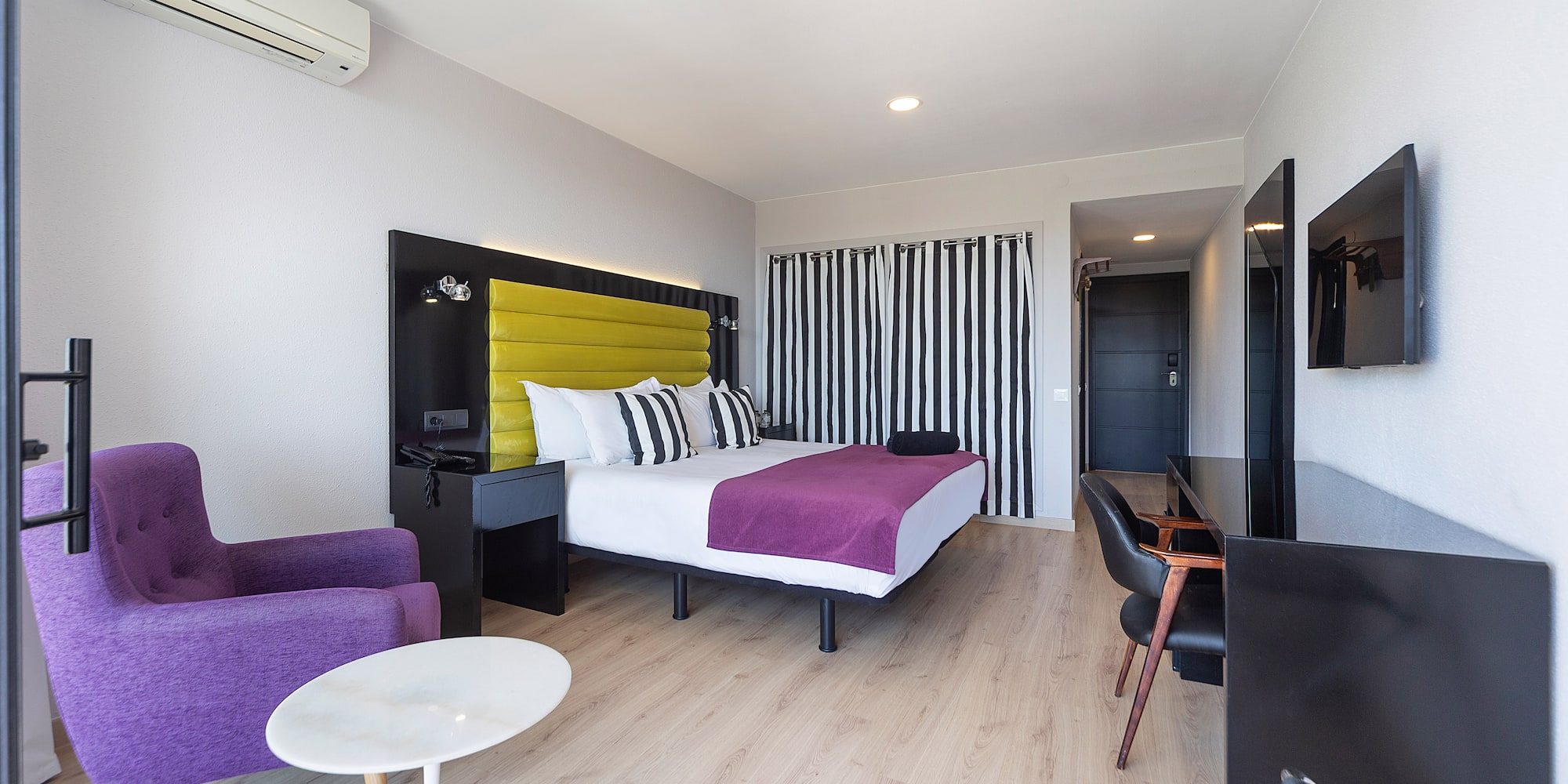 a room with a bed and purple chairs