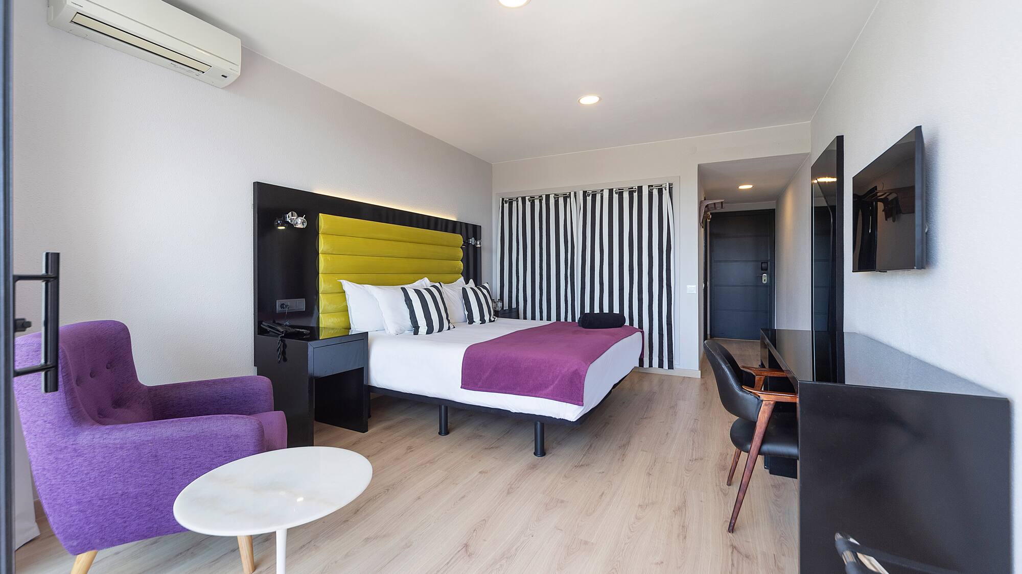 a room with a bed and purple chairs